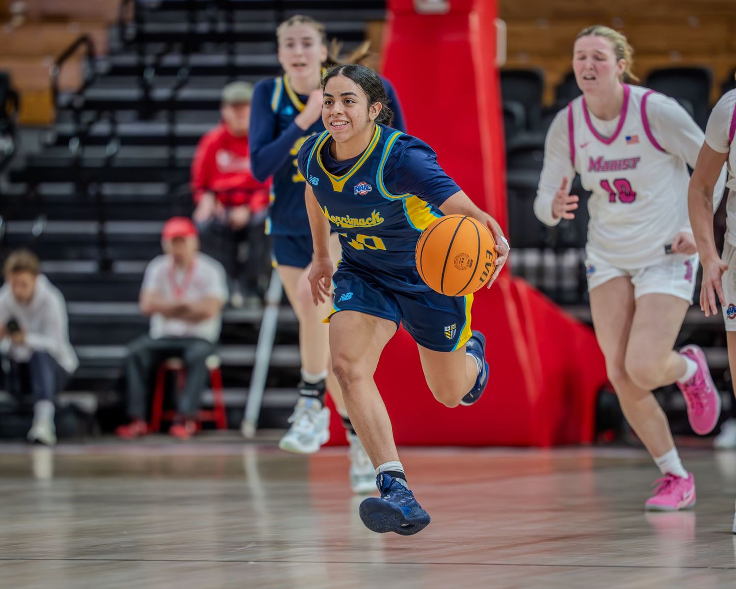 Basketball players dive for a loose ball during an intense game on the hardwood court.