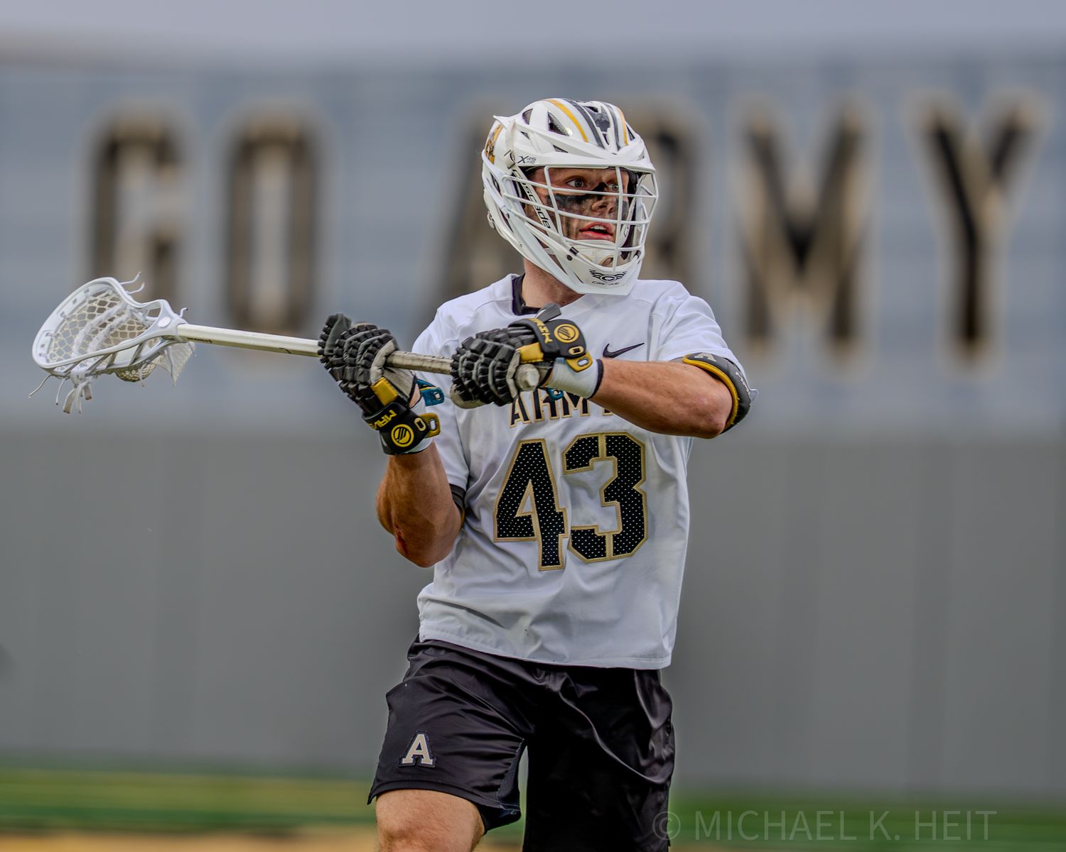 Lacrosse players from Army and Loyola competing for possession during a match.