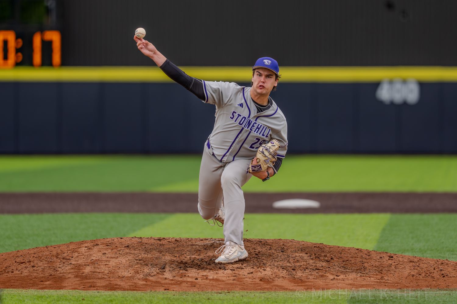 Baseball pitcher in motion delivers pitch from mound during game.