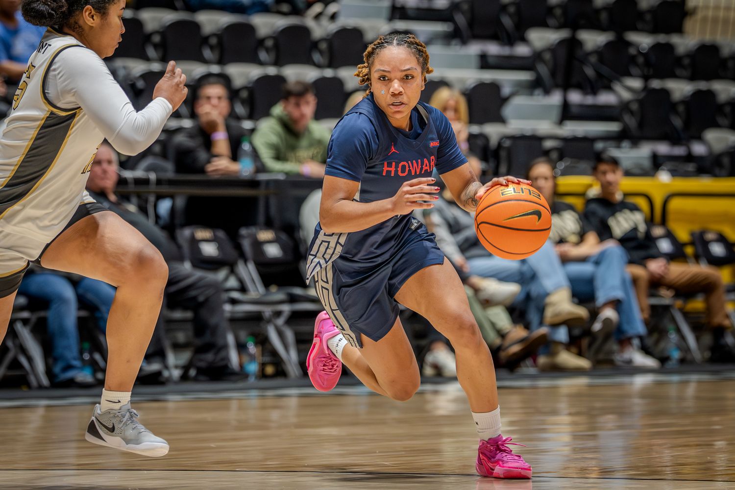 Basketball players in navy blue uniforms compete on a hardwood court during an intense game.