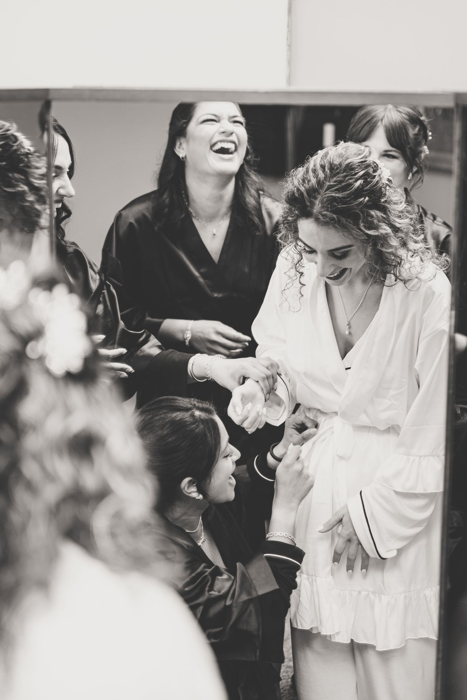 Bridesmaids laughing together in robes during wedding preparation getting ready.