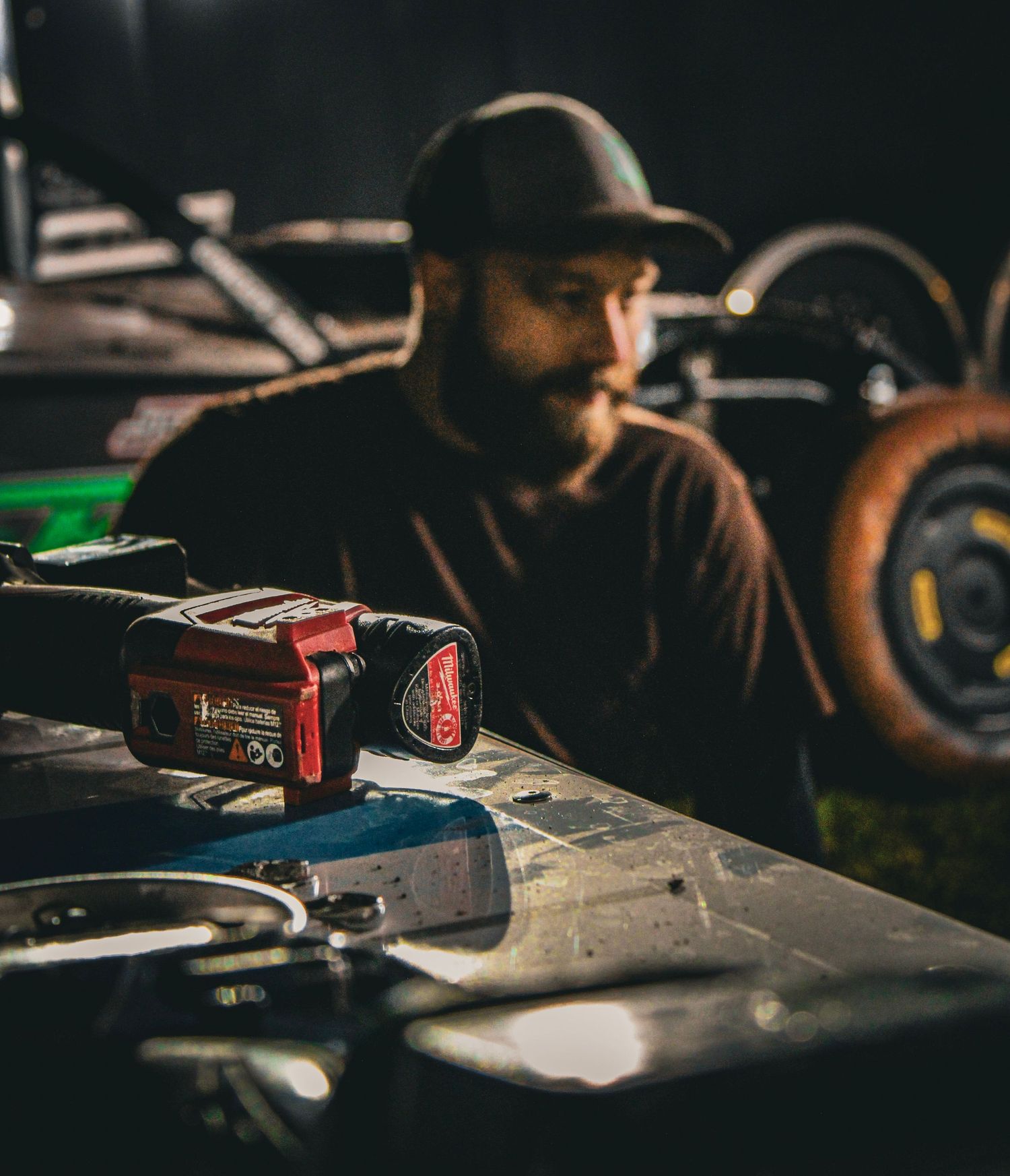 Dark moody workspace with tools and equipment scattered on wooden surface.