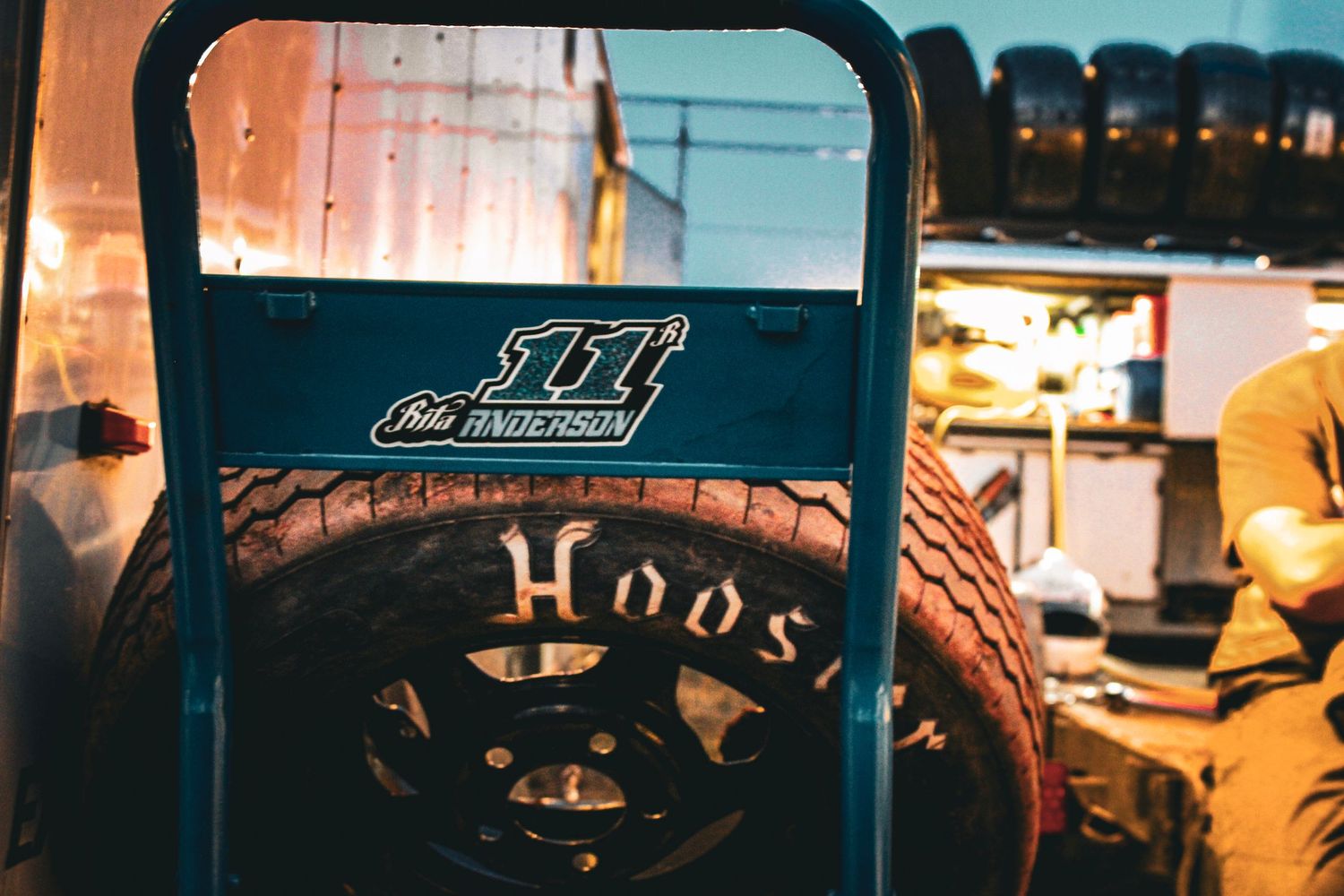 A Hoosier race tire sits on a tire stand.