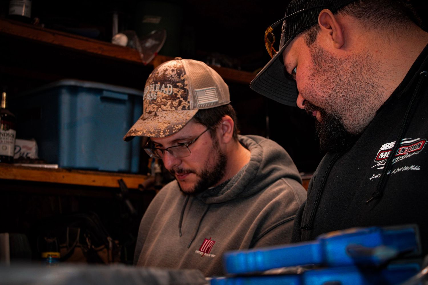 Workshop scene showing people working intently under blue-tinted lighting.