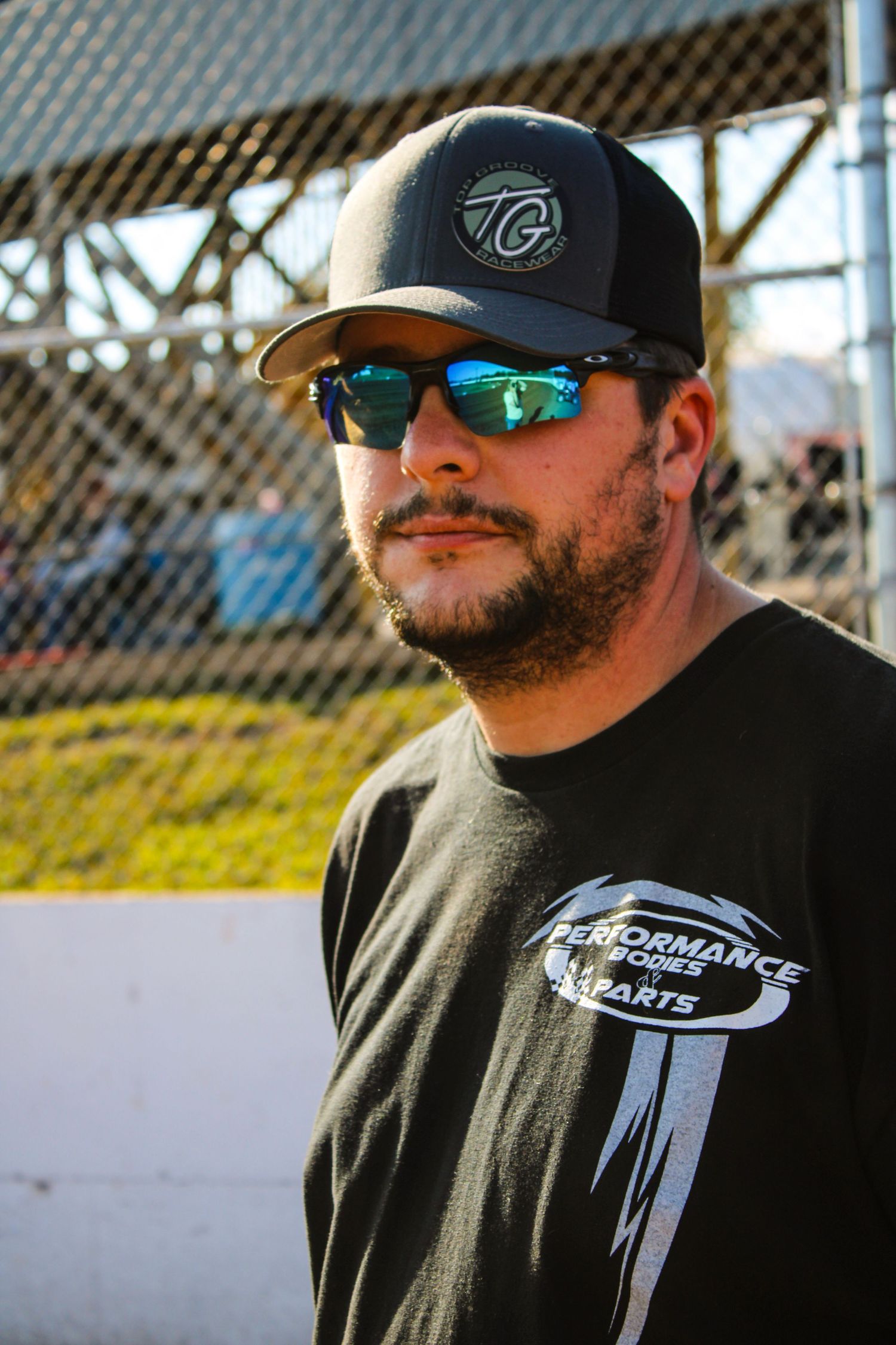 Person wearing a black cap and sunglasses with reflective lenses against a blurred background.