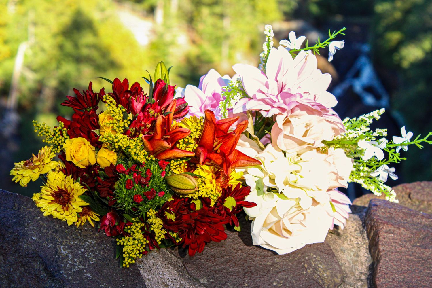 Colorful floral arrangement with yellow, red and pink flowers displayed outdoors.