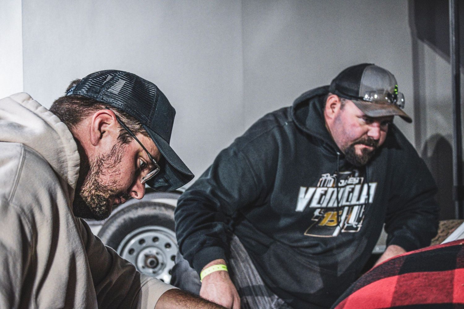 Mechanics in black jackets working on equipment in a bright workshop.
