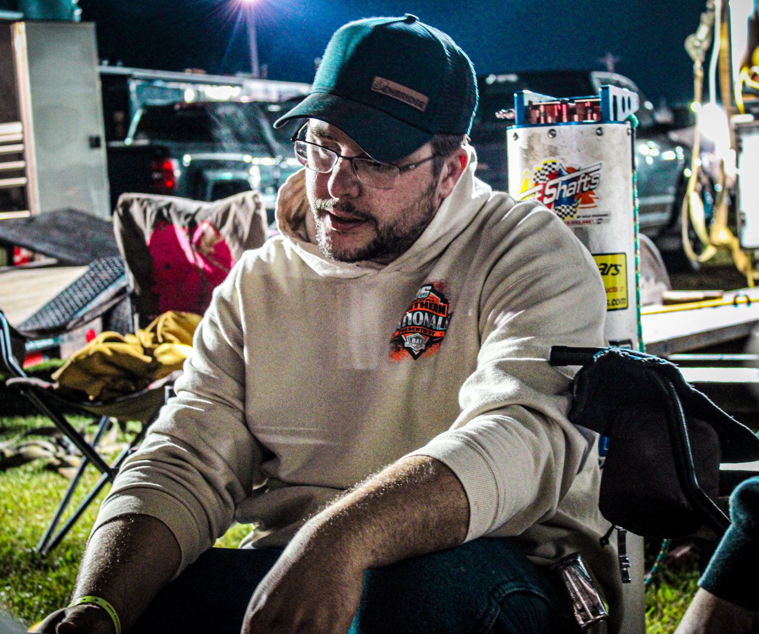 Person in light colored sweater working at night under bright lighting.