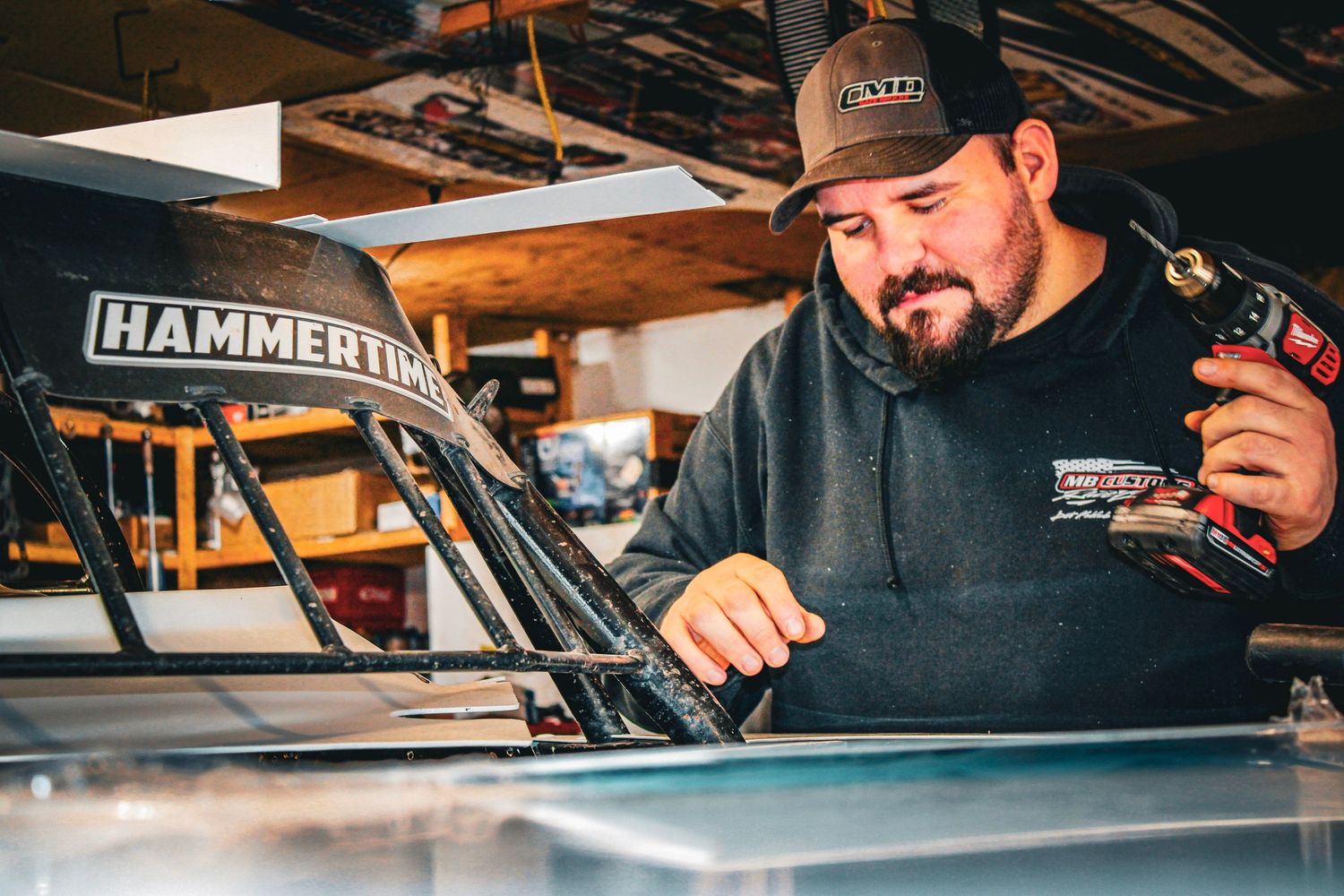 Mechanic working on a race car in a garage workshop with Hammerin branding visible.