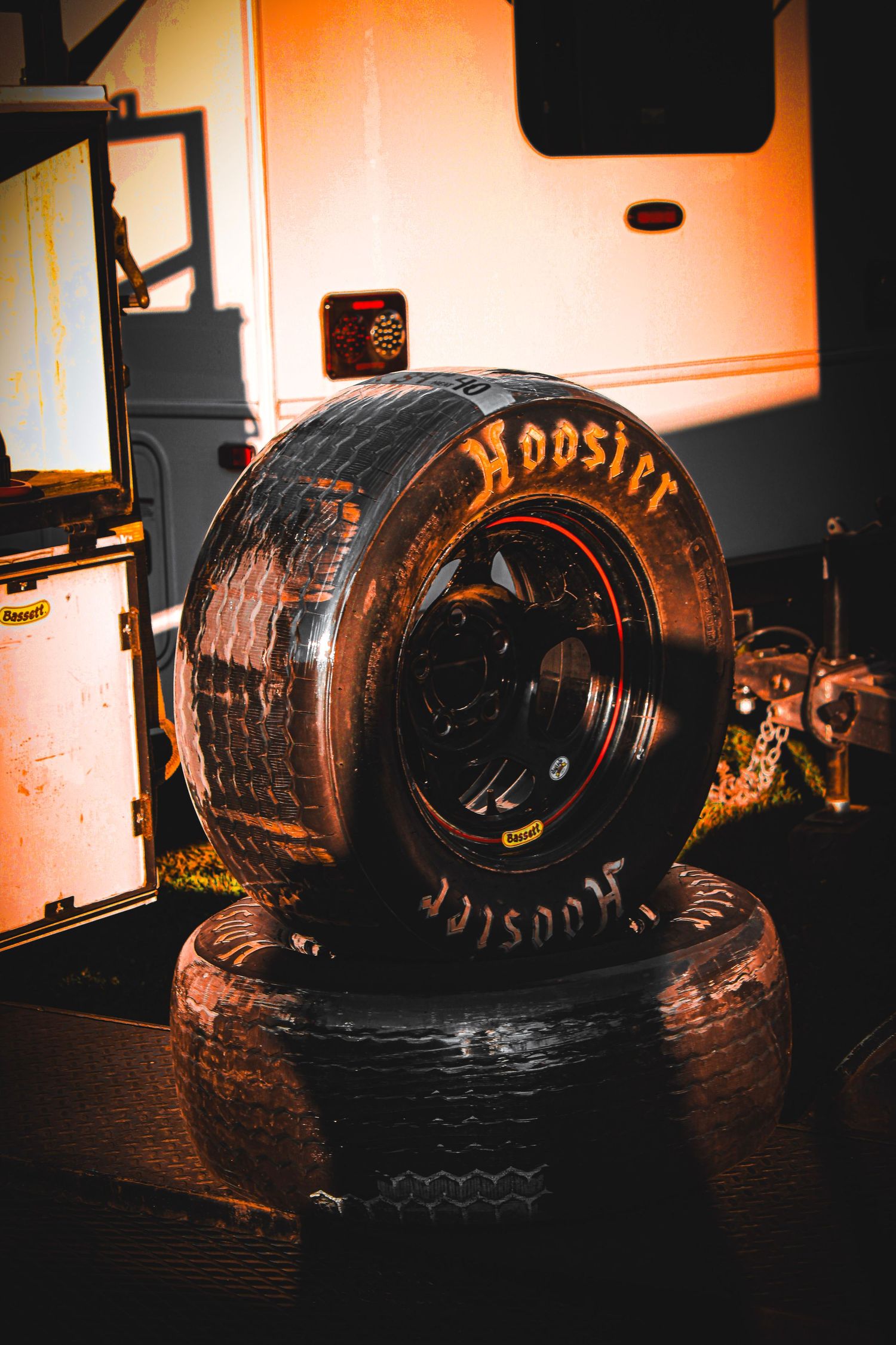 Used Hoosier racing tires arranged in dark lighting conditions.