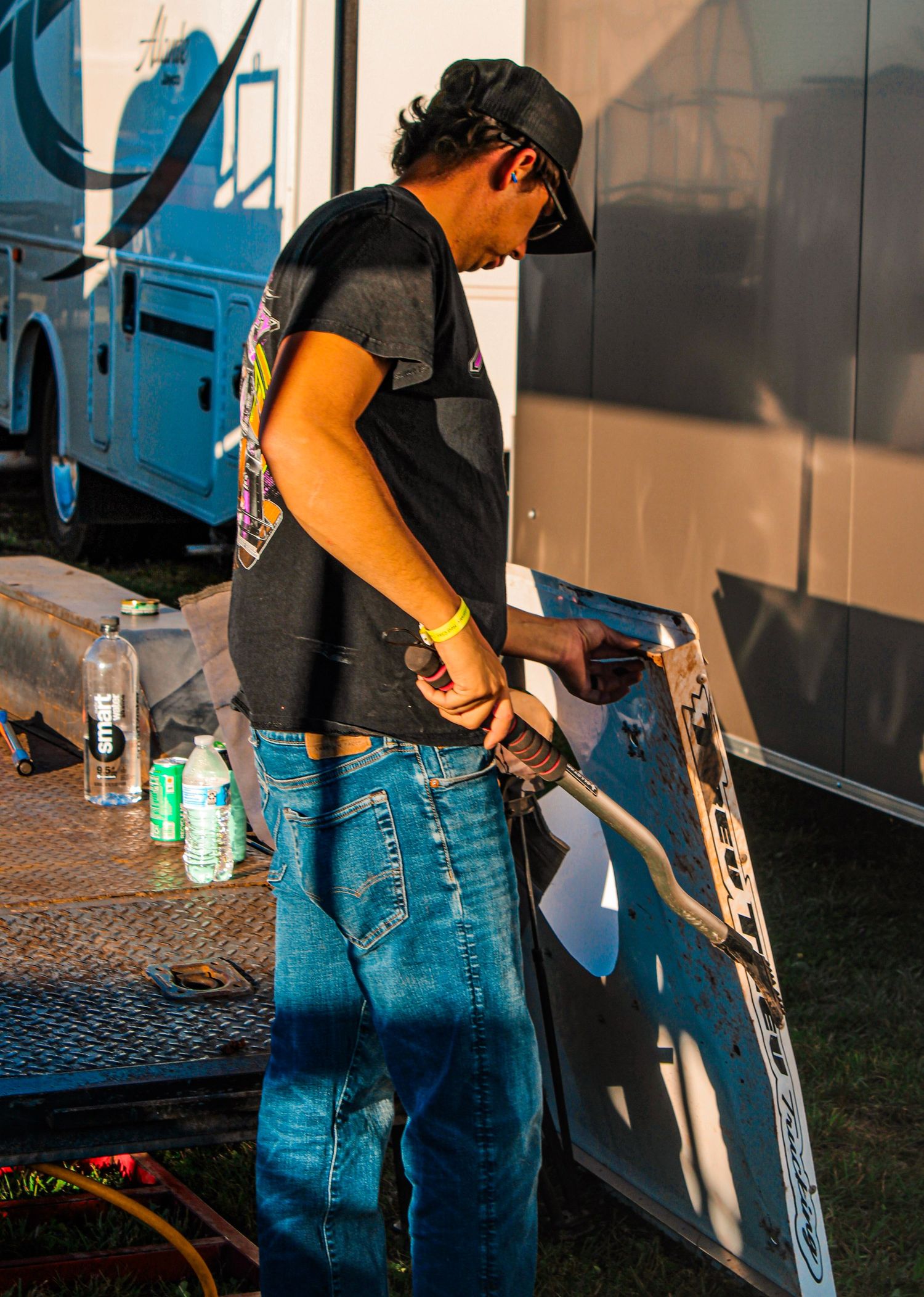 Person in jeans working with tools and equipment near a vehicle.