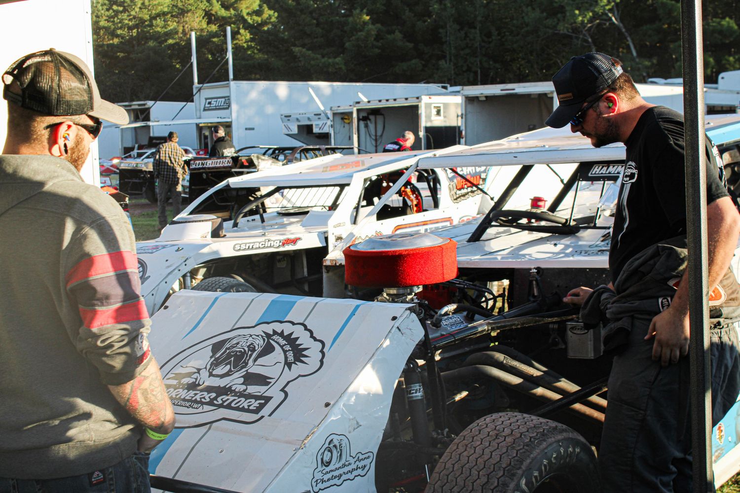 Race cars lined up in an outdoor parking area during daytime.
