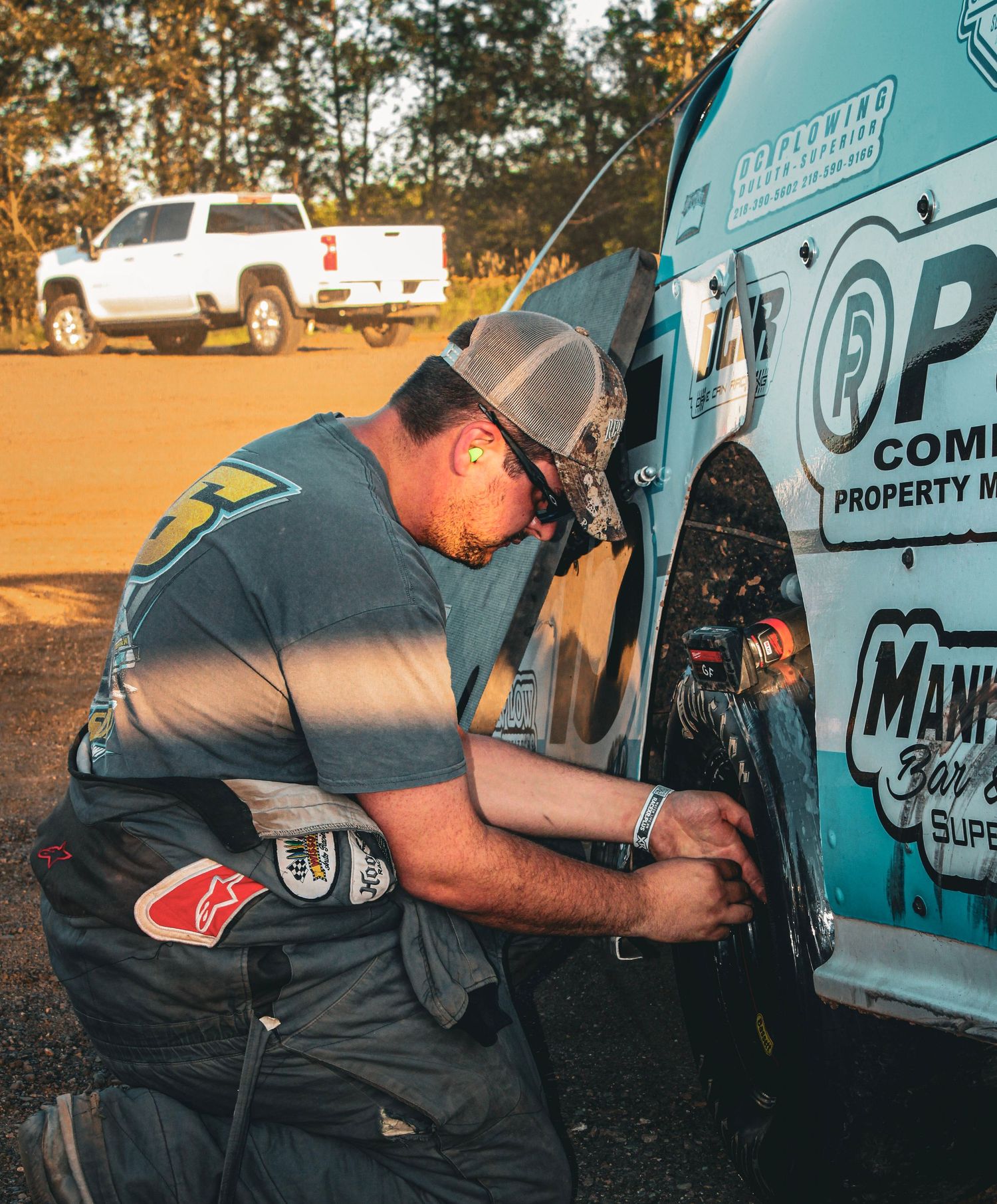Professional property maintenance worker using power tools to repair equipment in an outdoor setting at dusk.