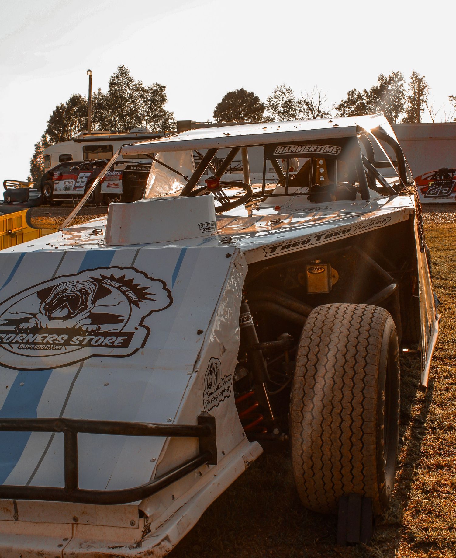 White race car body panels with blue stripes and sponsor decals on display.