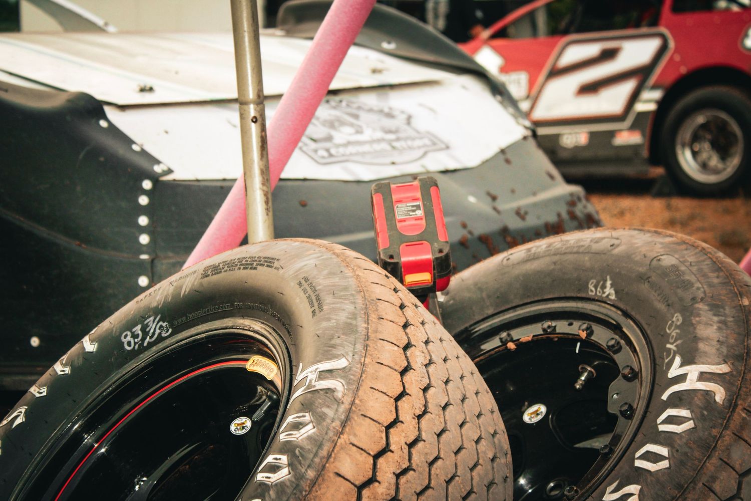 Close-up view of a racing tire tread pattern showing hexagonal grip patterns and wear marks on a black rubber surface.