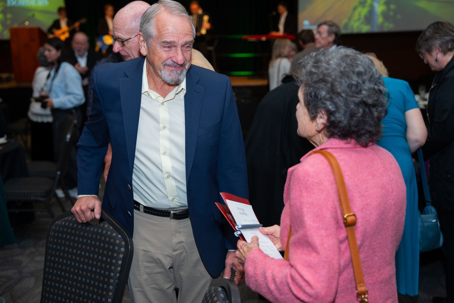 People mingling at an indoor event with blurred background lighting.