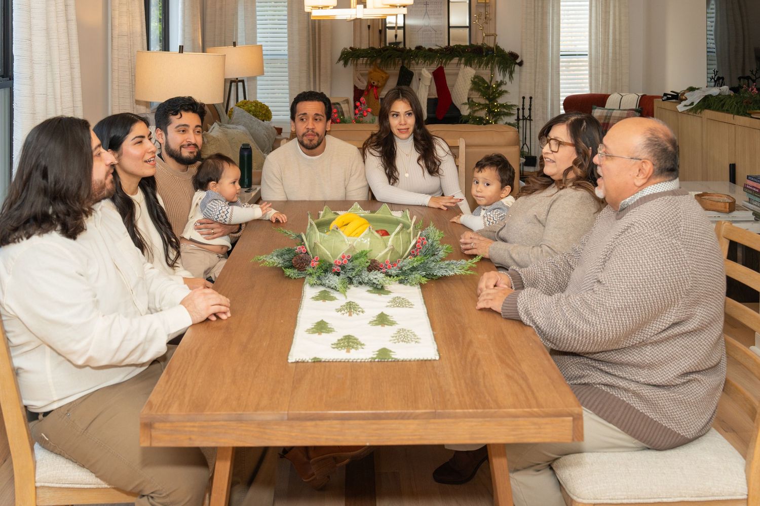 Family members gather around a wooden dining table for a casual meal and conversation at home.