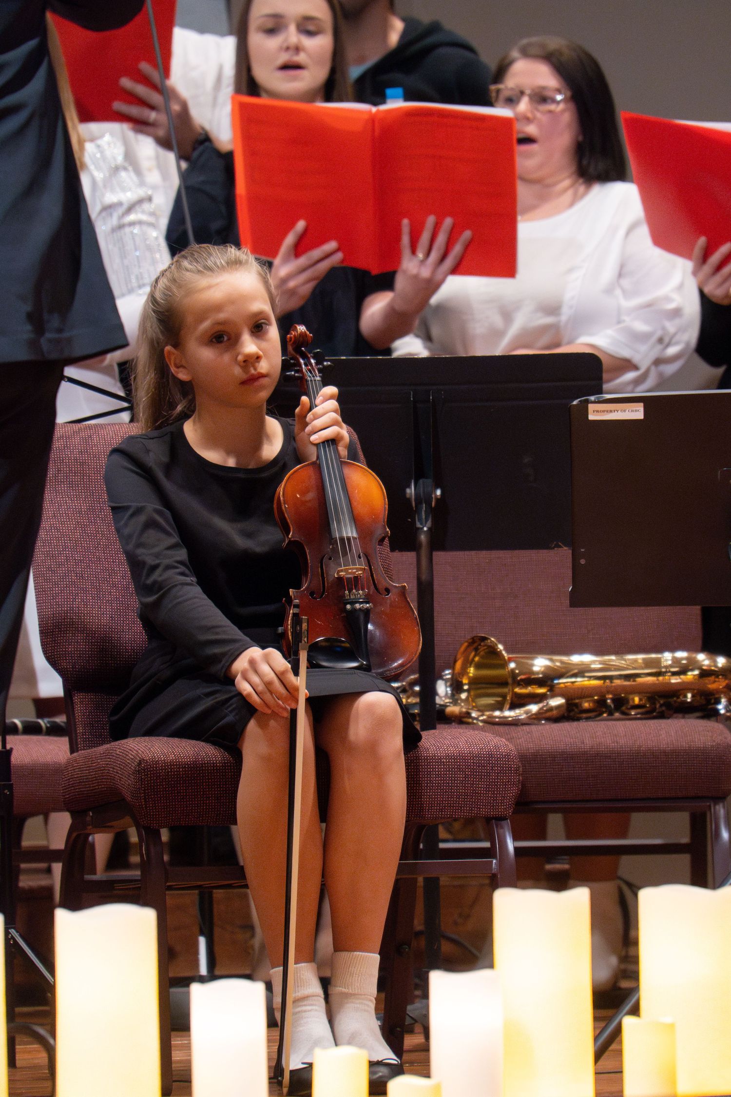Musicians perform with violins beside glowing candles during evening concert.