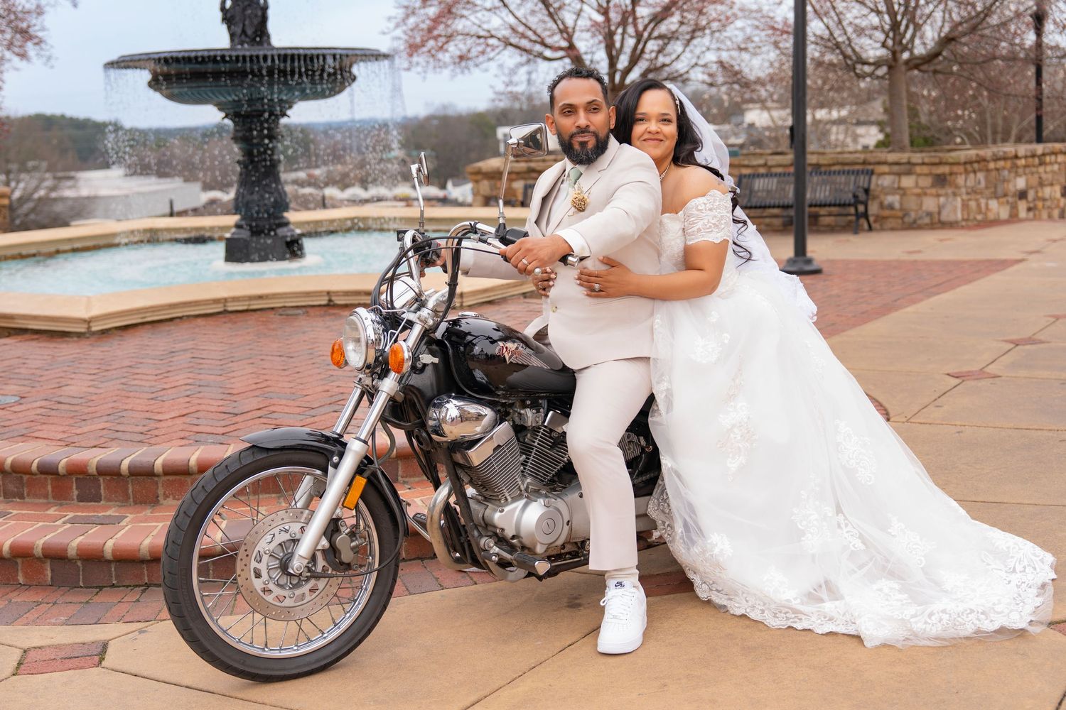 A classic motorcycle displayed outdoors with a white lace dress draped beside it.