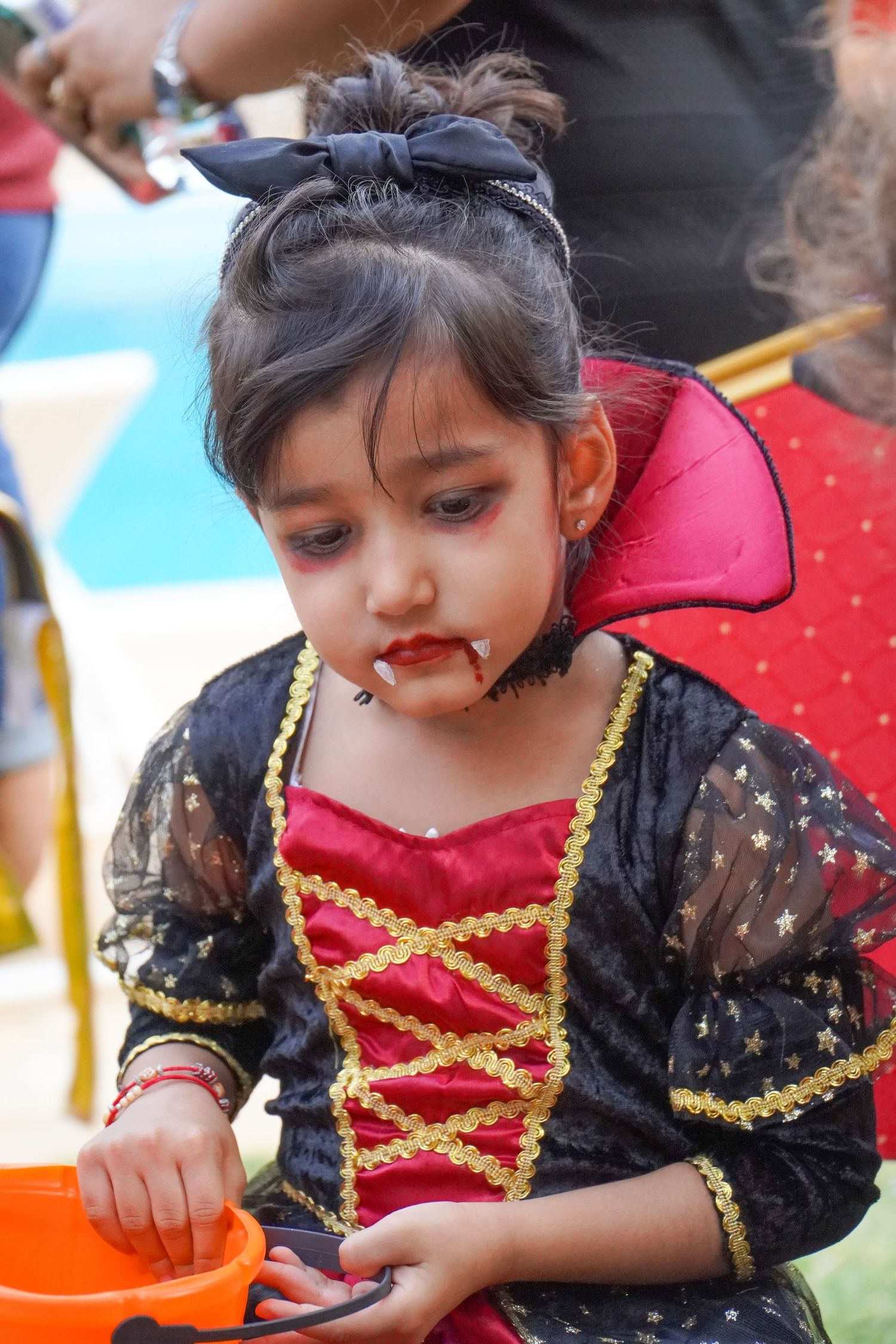 Child wearing elegant black and red princess costume with gold trim details.