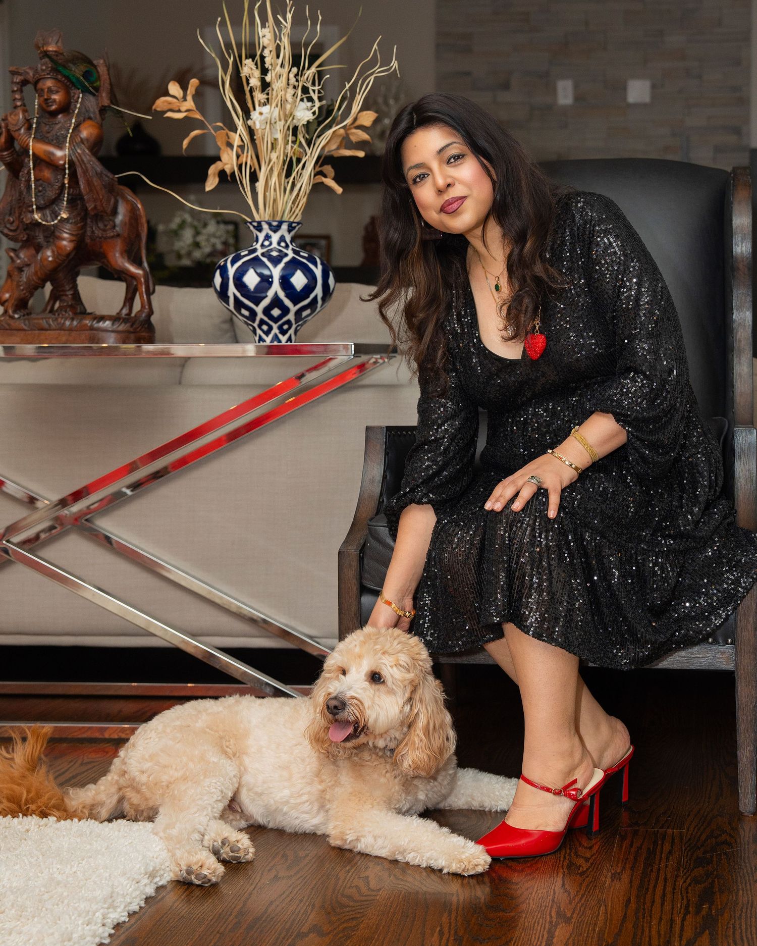 A sequence of photos showing someone in a sparkly black dress and red heels playing with a fluffy cream-colored dog on the floor.
