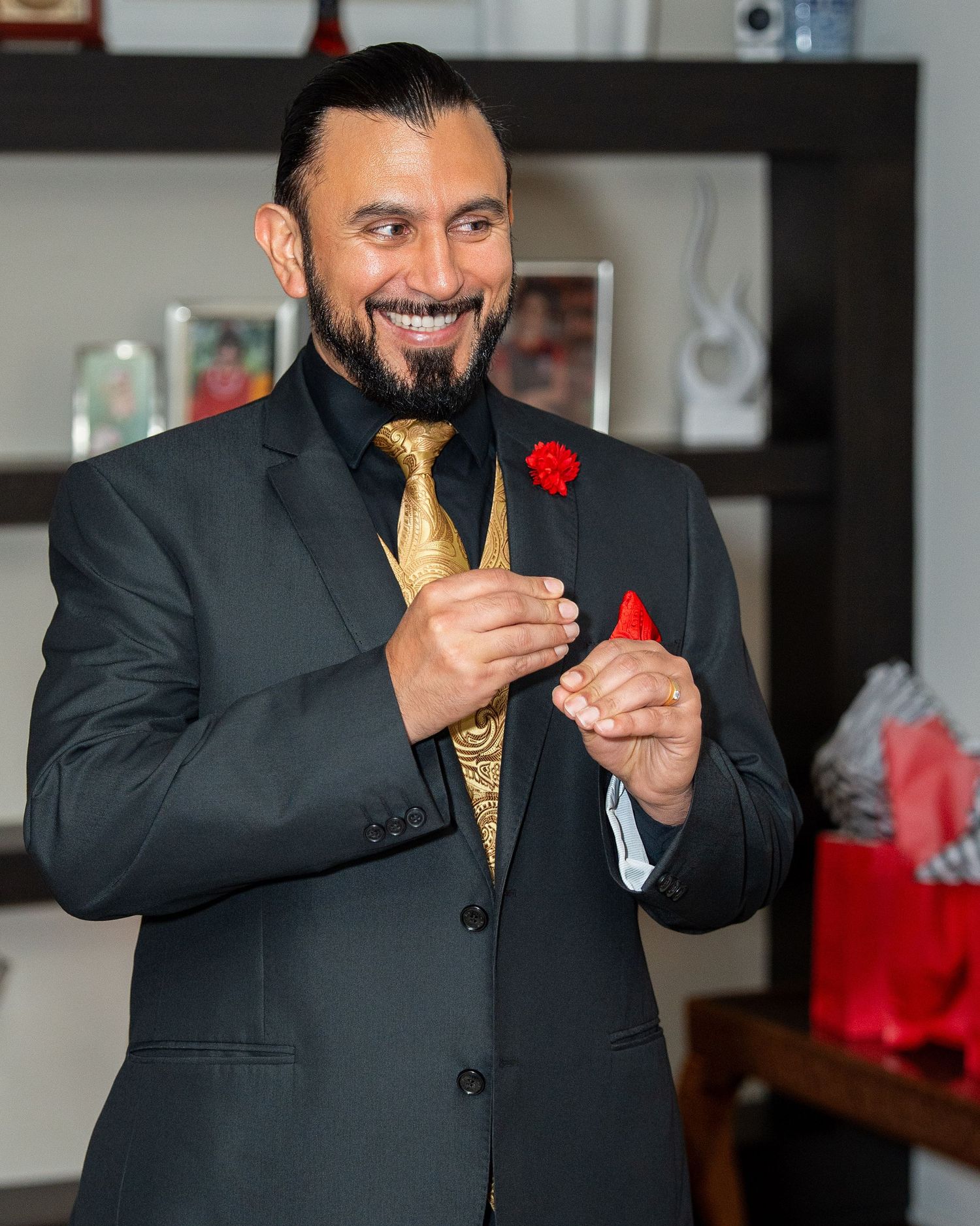 A person in a dark suit and yellow tie smiles while holding a martini glass during a celebration.