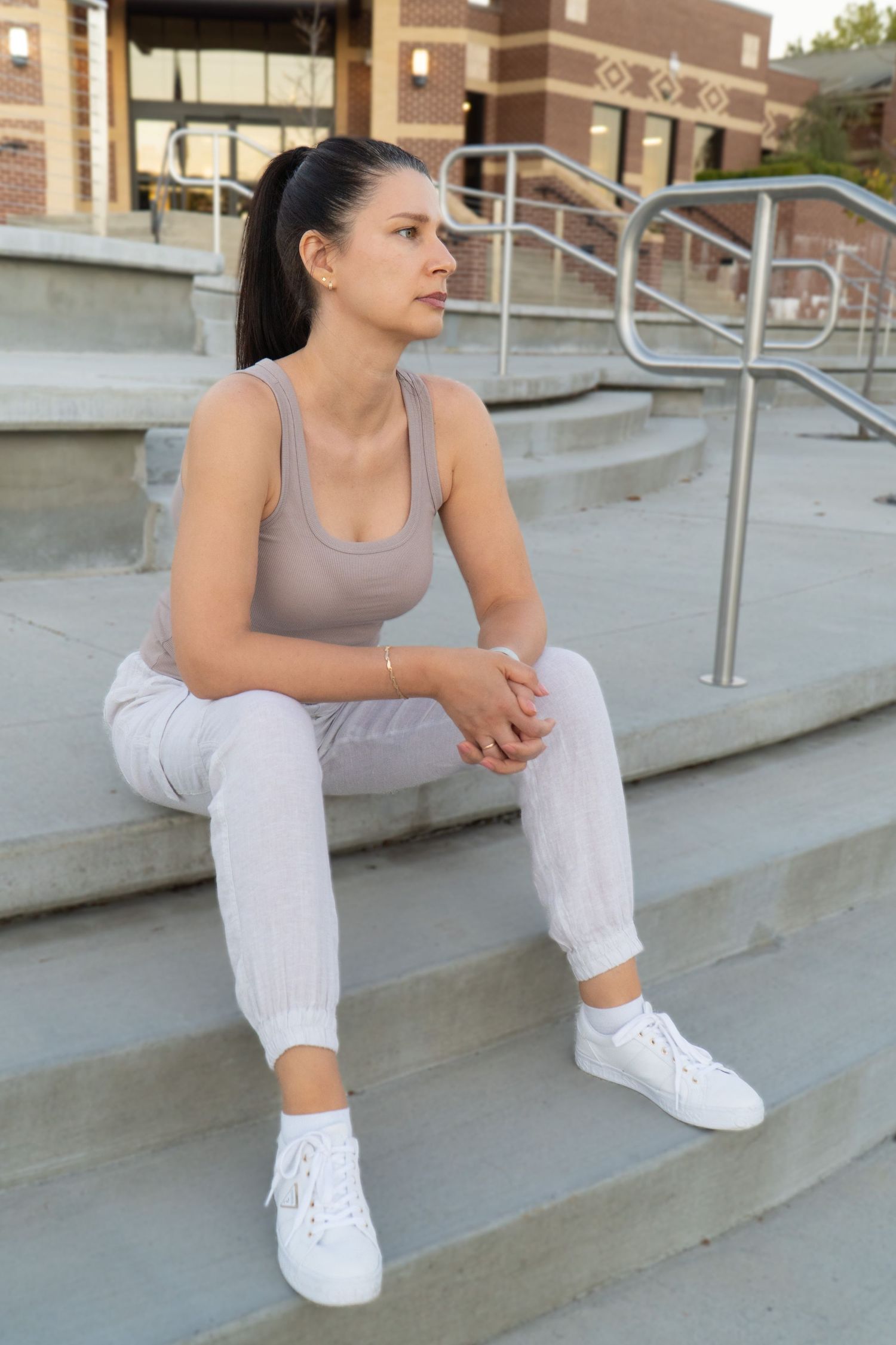 Person in athletic wear sitting on concrete steps in casual urban setting.