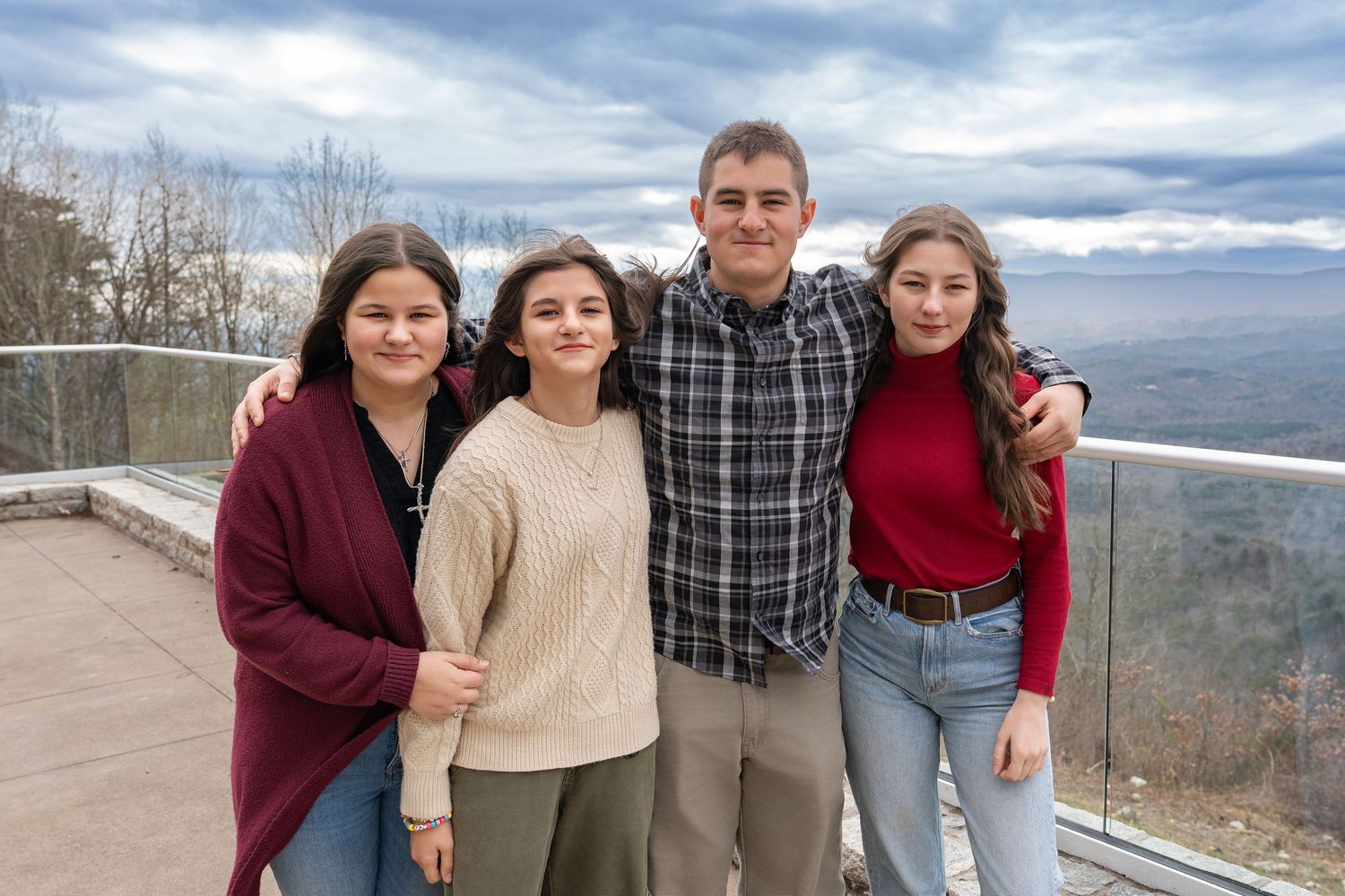 A group stands together at a scenic mountain overlook on a cloudy day.