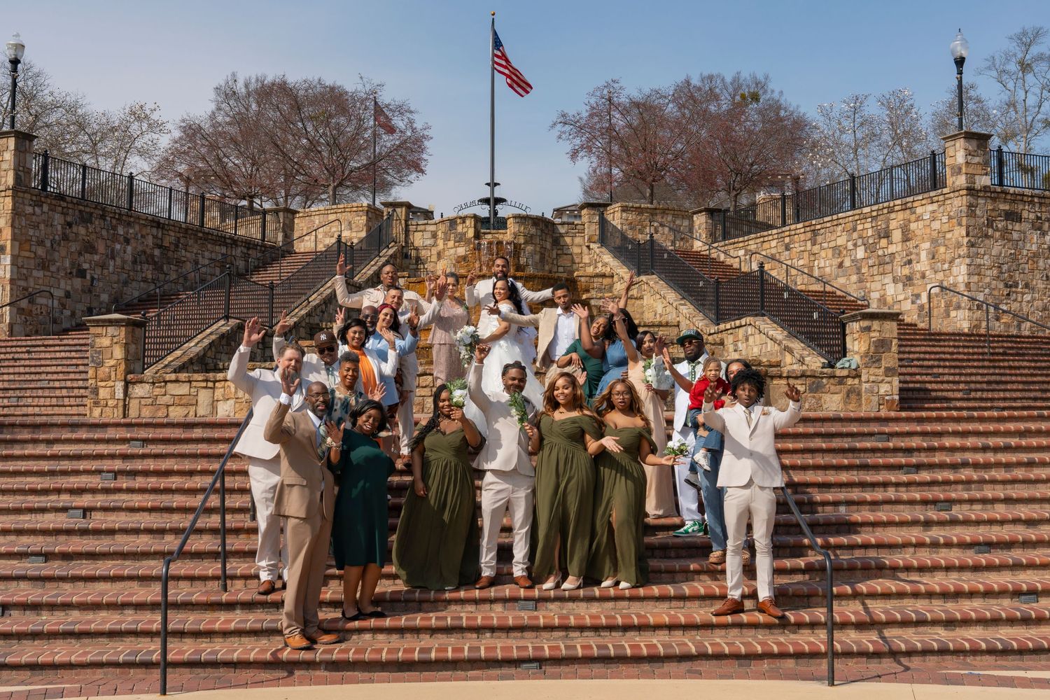 A group of people sit on wide stone steps during a sunny day outdoors.