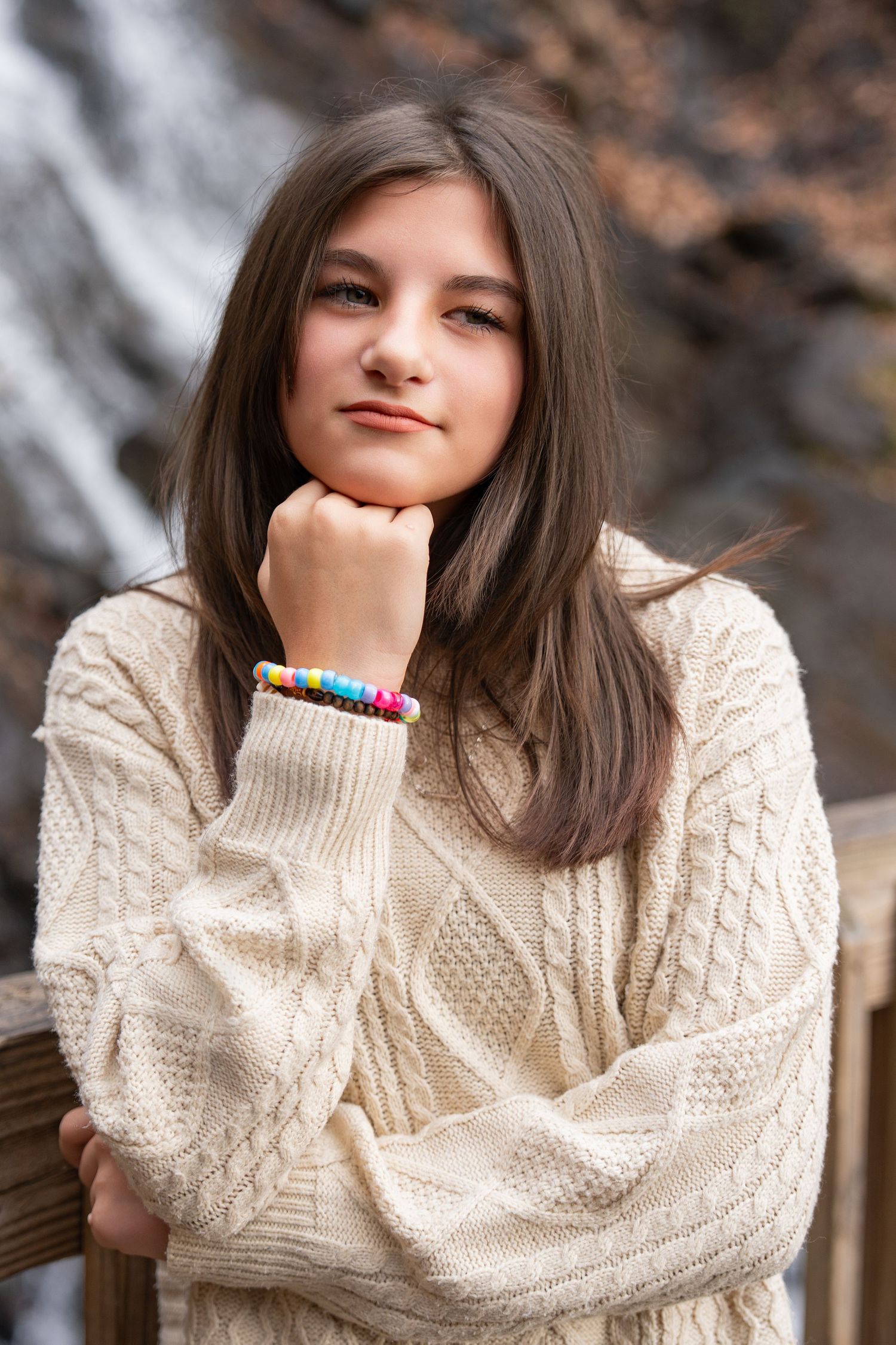 A person in a cozy cream cable knit sweater poses playfully in a series of outdoor portrait shots.
