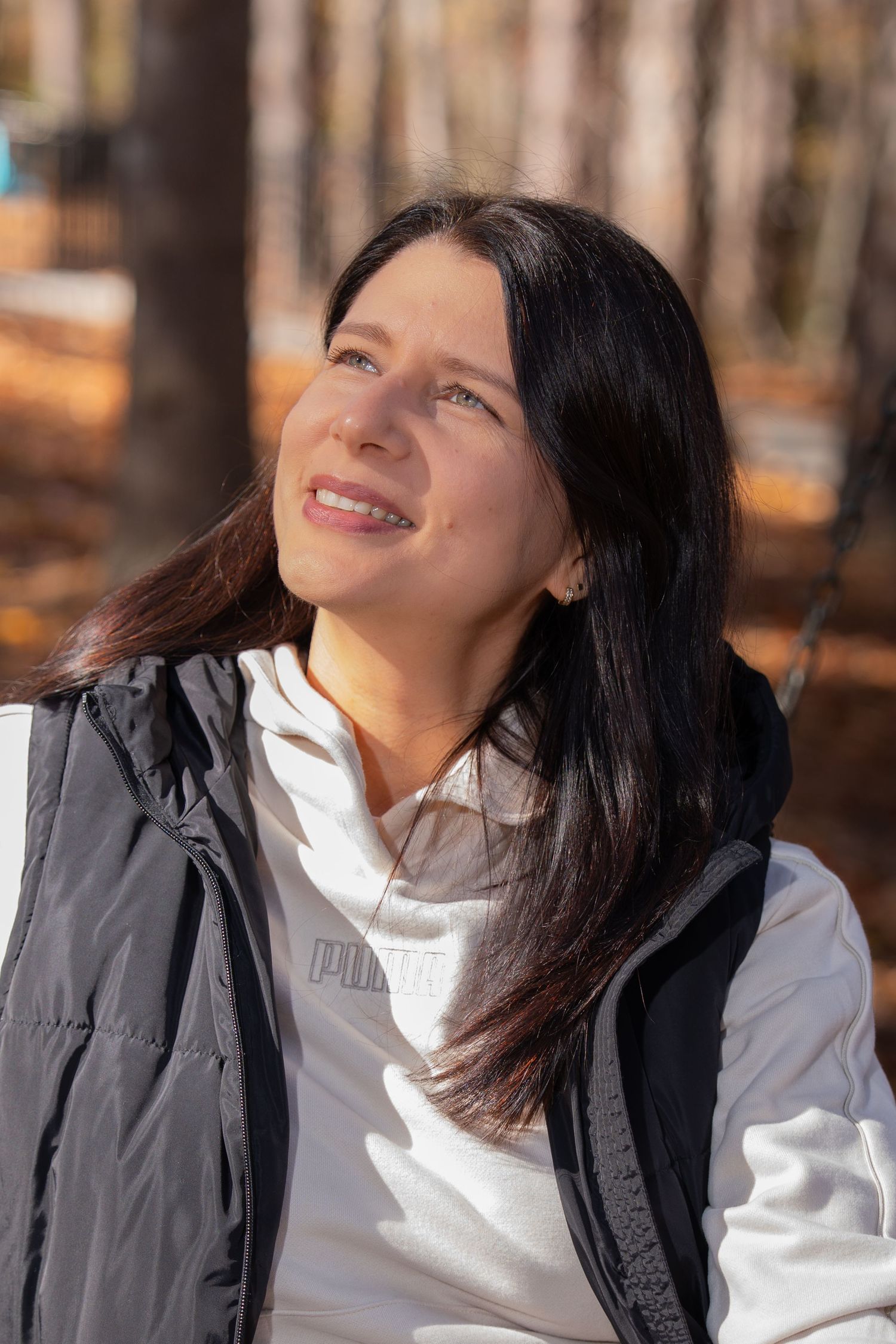 Person in white and black outfit smiles while enjoying autumn scenery.