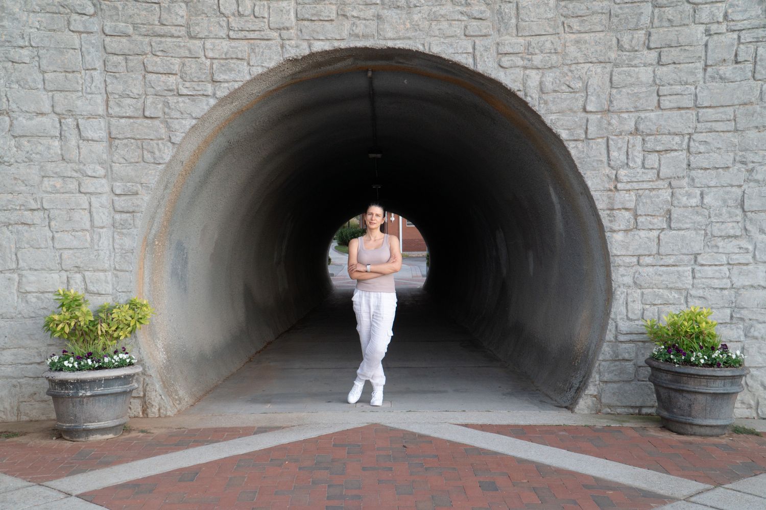 Person in athletic wear jogging through a stone tunnel with planters.