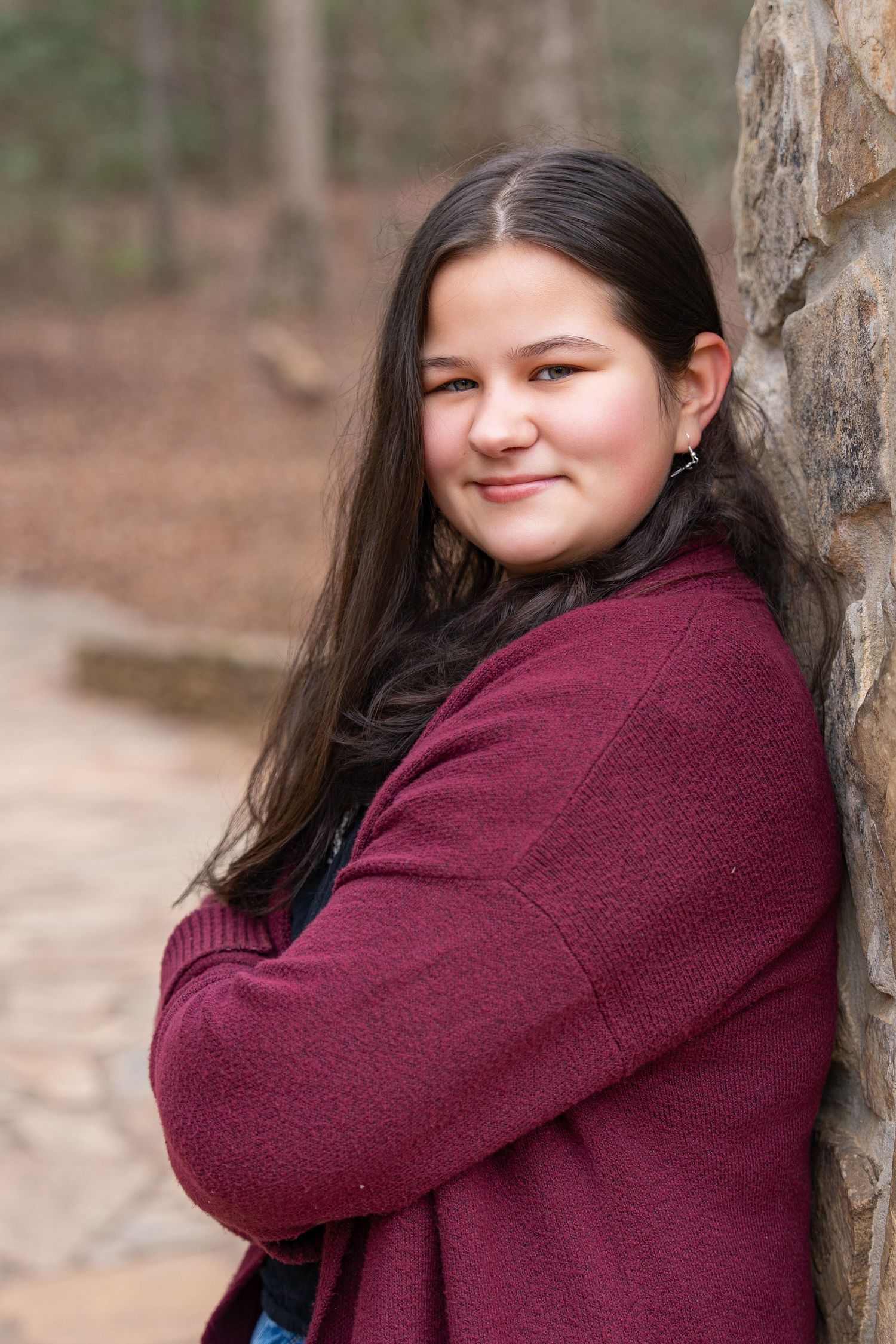A person in a burgundy sweater poses against a stone wall in a series of casual outdoor portraits.