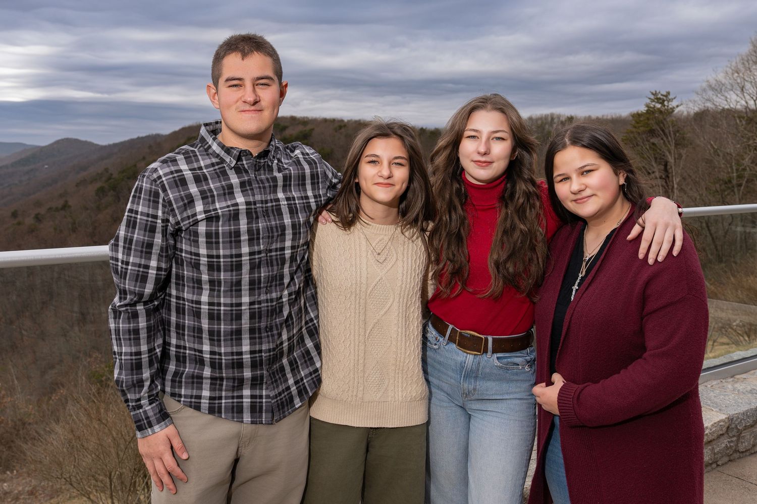 A group stands together against a scenic mountain backdrop on an overcast winter day.