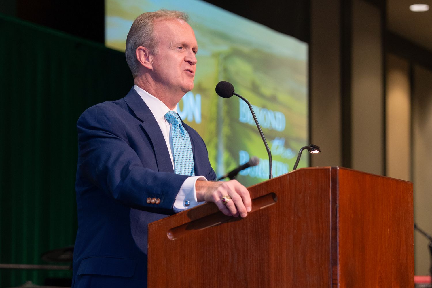 A speaker presents at a wooden podium during a professional conference.