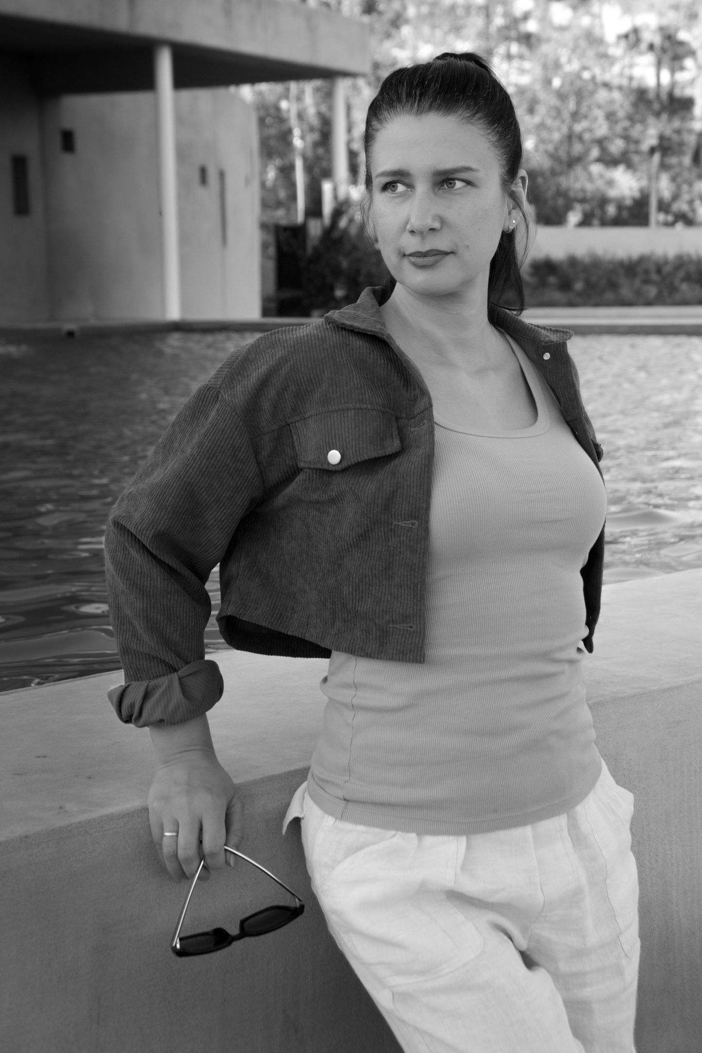 Person in gray top and white pants posing outdoors.