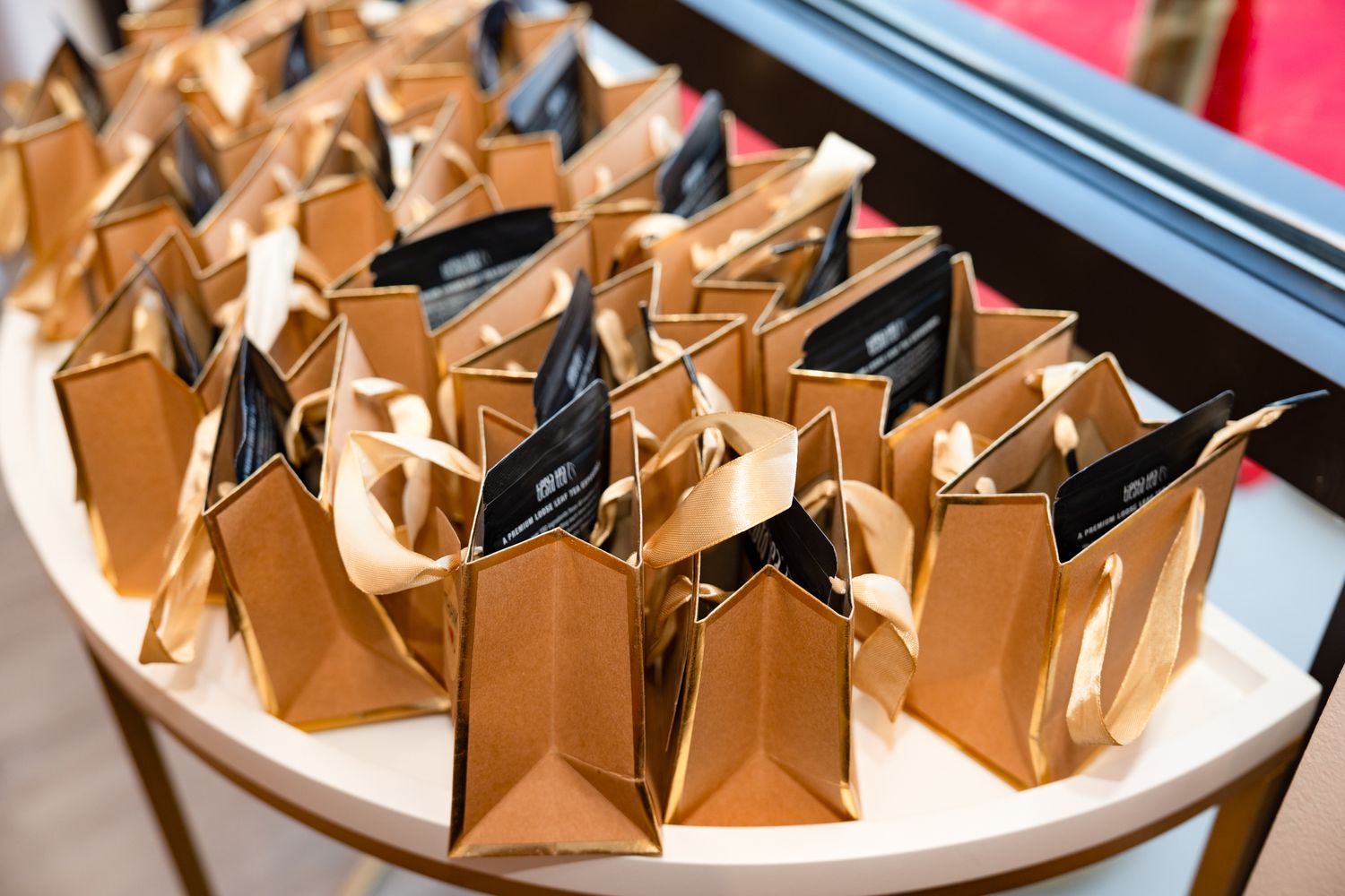 Brown paper gift bags arranged in rows on a white surface at an event.