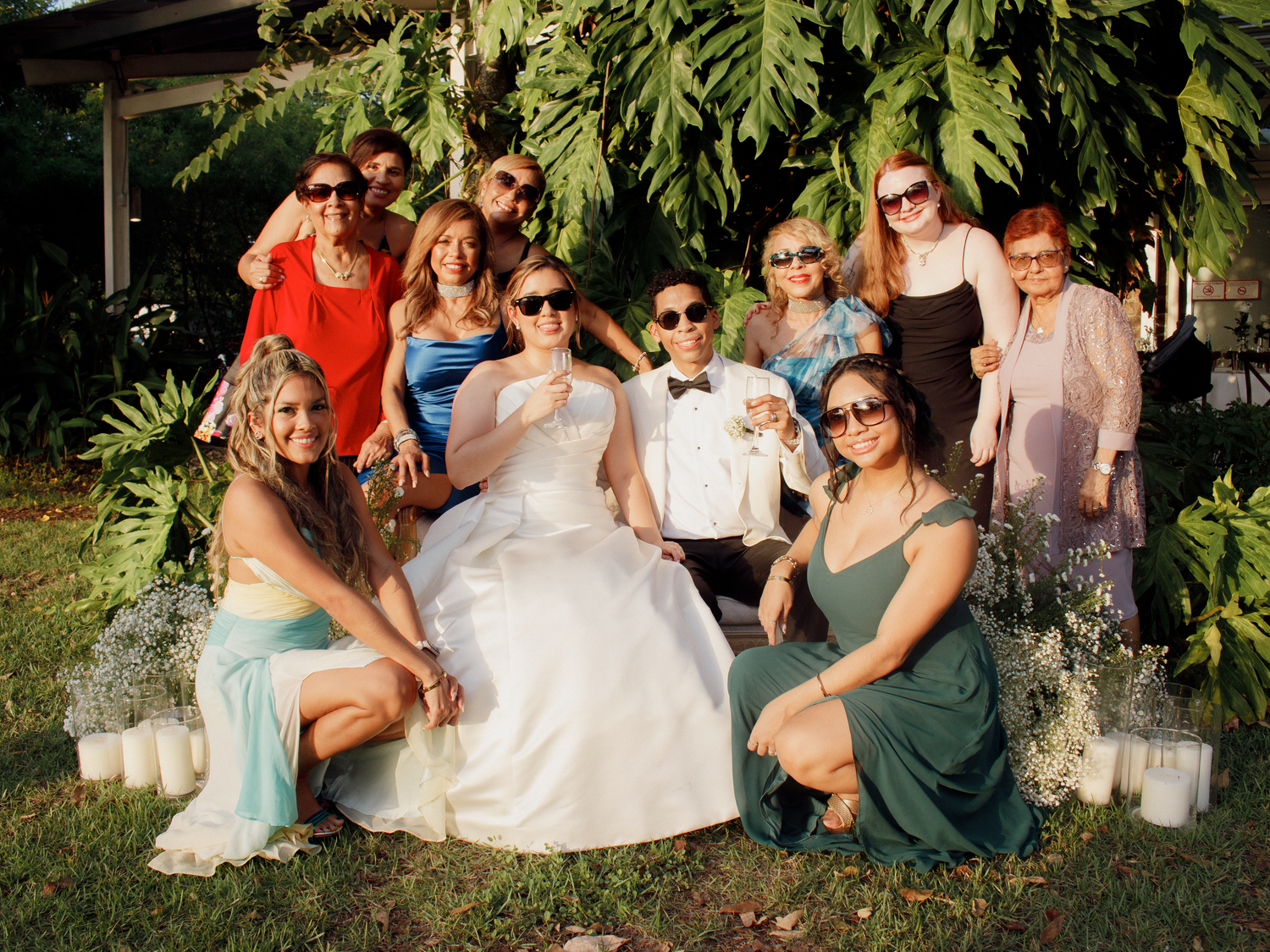 Wedding guests relaxing on lawn with lush tropical greenery.