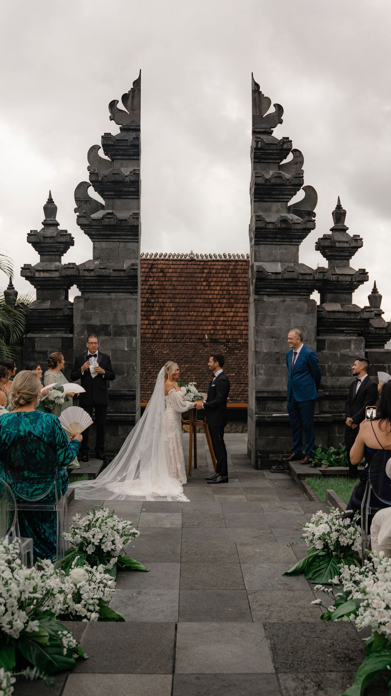 An elegant outdoor wedding ceremony setup with stone pillars and floral arrangements.