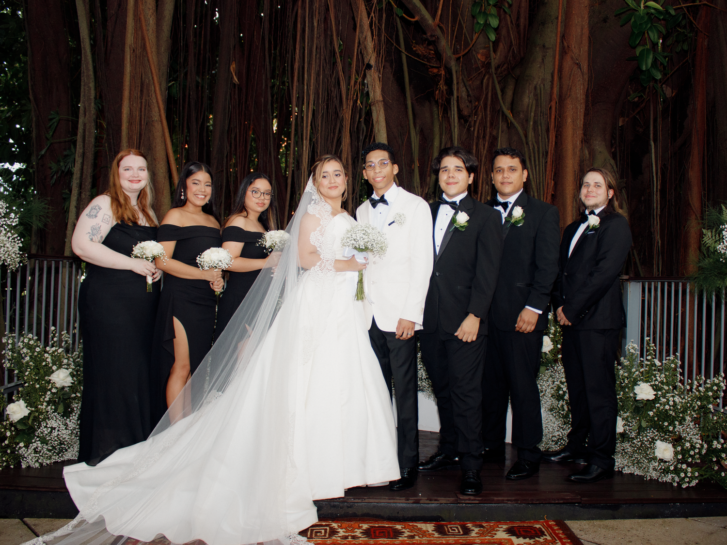 Wedding celebration under string lights with tropical foliage backdrop.
