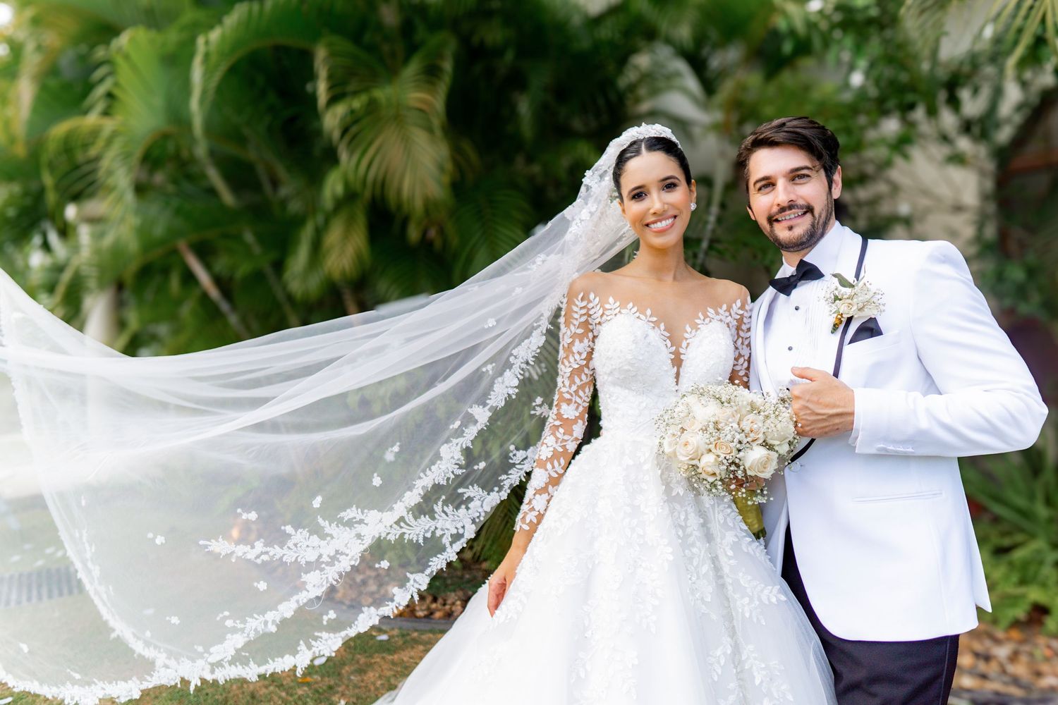 Romantic outdoor wedding photoshoot with flowing veil and natural garden backdrop.