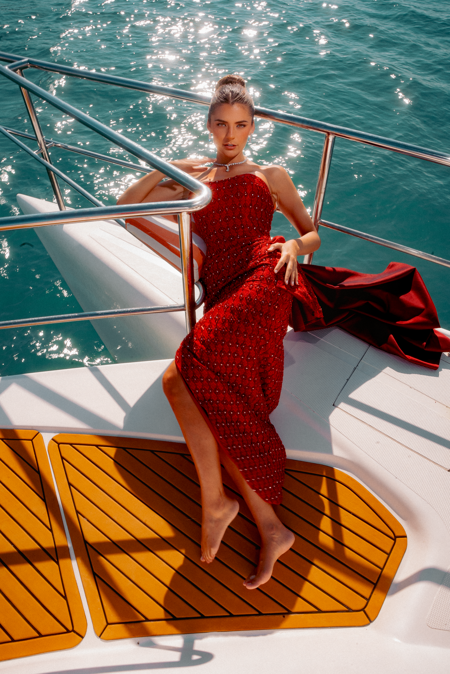 Woman in red polka dot dress lounging on yacht deck in bright sunlight.