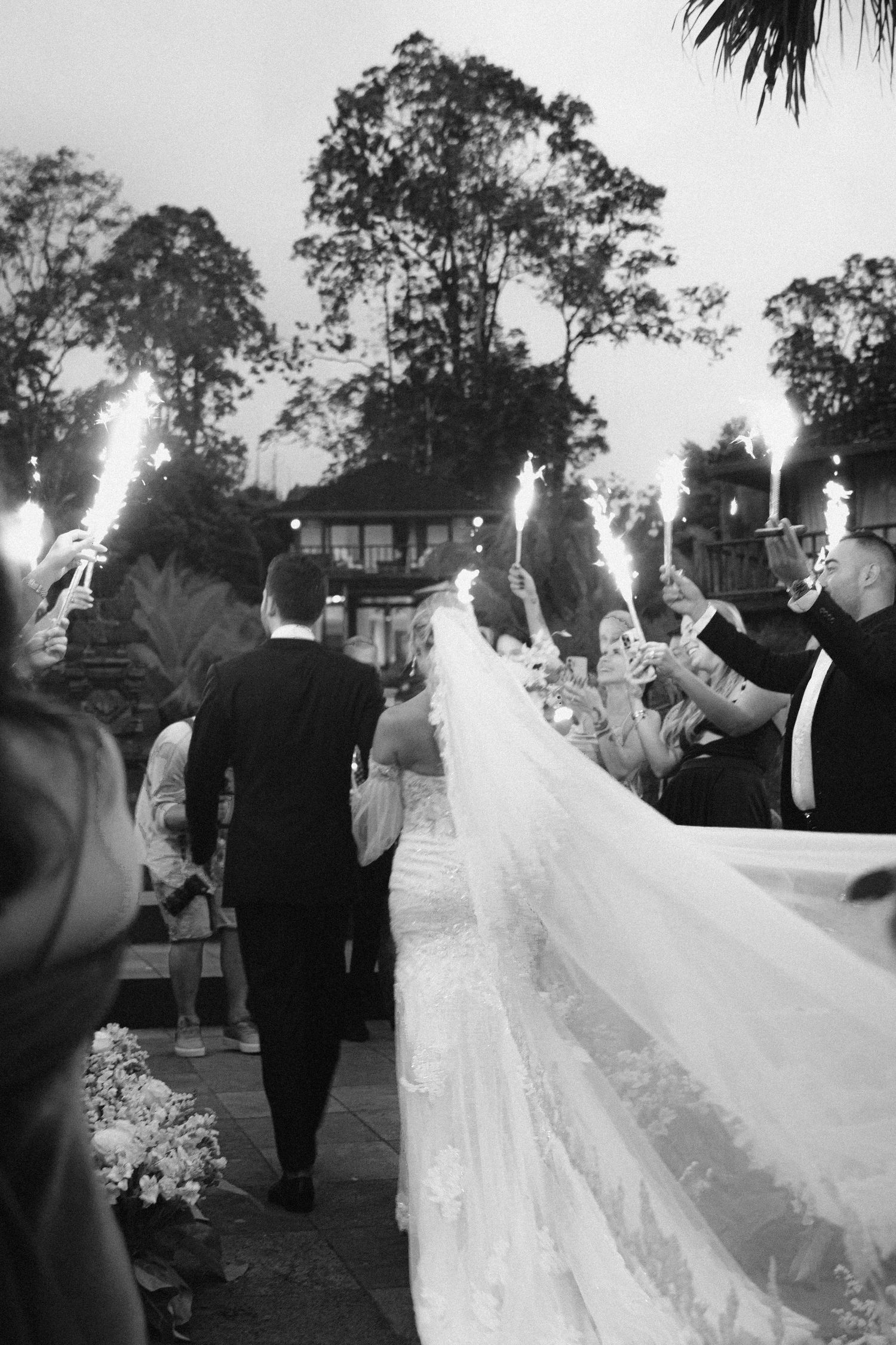 Wedding party holding sparklers during an outdoor evening celebration.