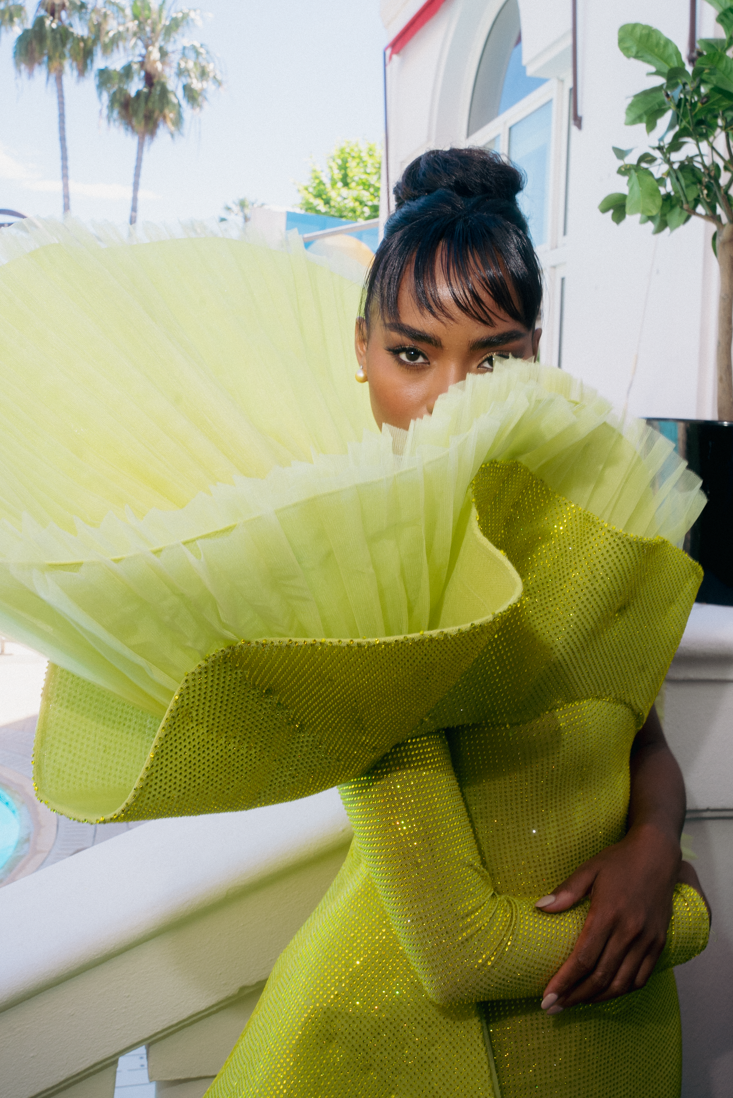 Model posing in a dramatic lime green tulle gown against a bright outdoor backdrop.