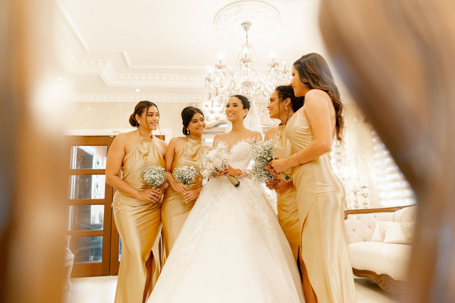 Bridal party in champagne dresses preparing in sunlit room.