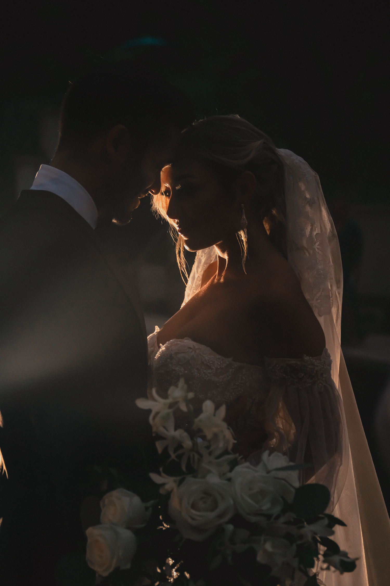 Artistic low-light wedding photography with soft focus on bridal details.