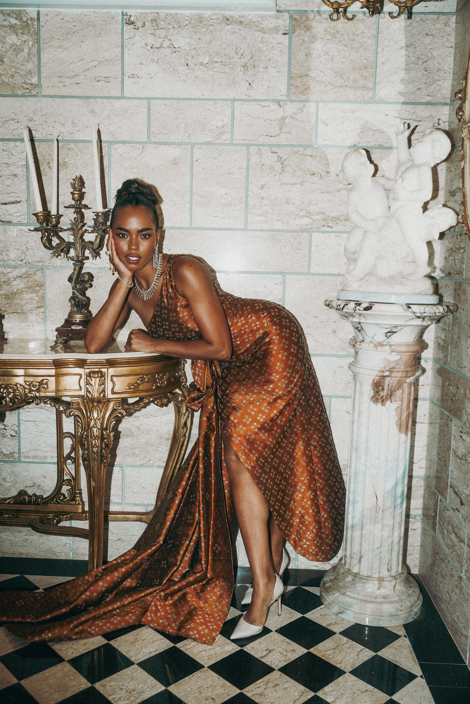 Four artistic fashion photos showing a model in a shimmering copper dress posing on a checkered floor against white walls.