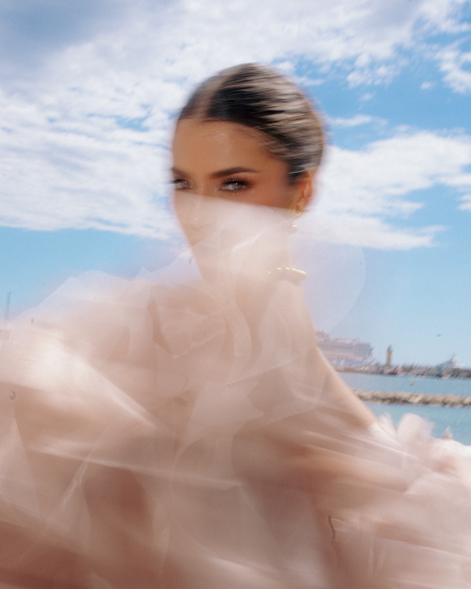 Ethereal fashion photography featuring a flowing pink dress against blue sky.
