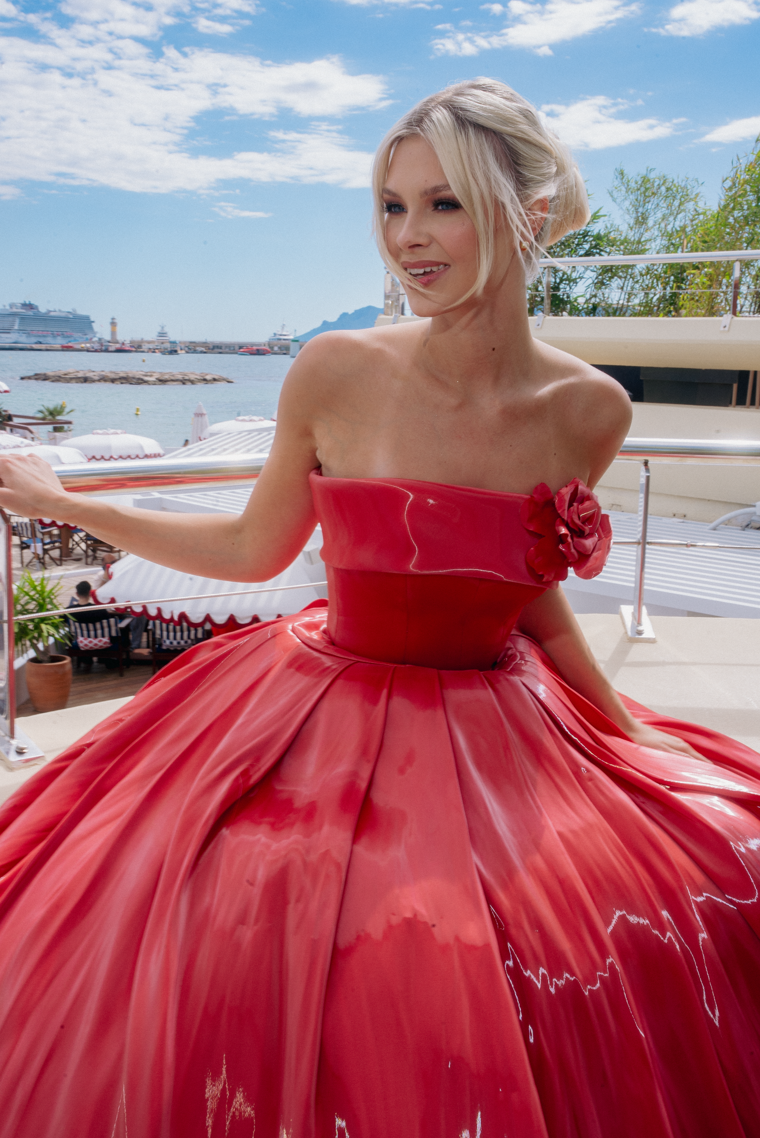 Vibrant red formal dress with voluminous skirt captured in outdoor photoshoot.