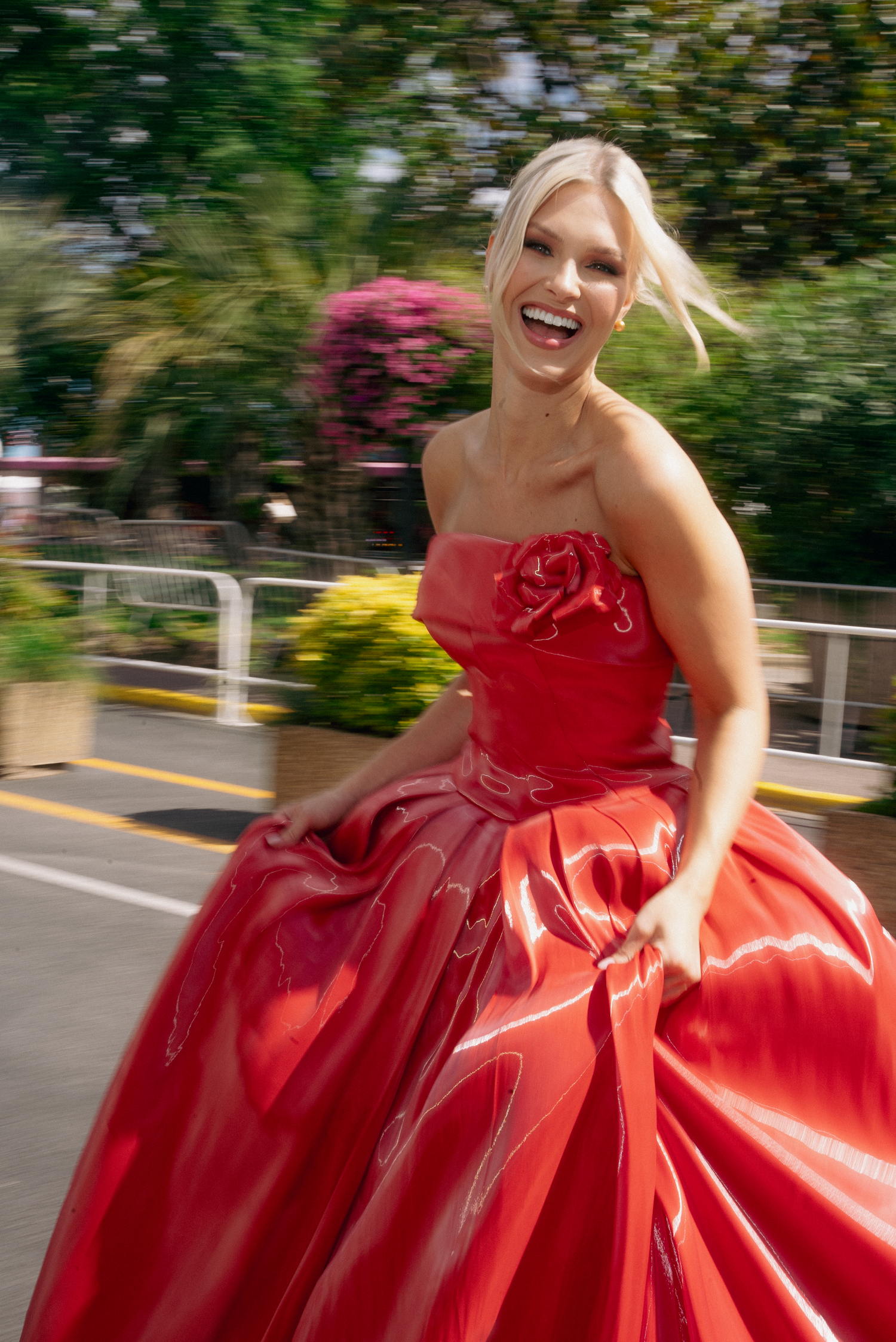 Flowing red ballgown twirls against tropical garden setting.